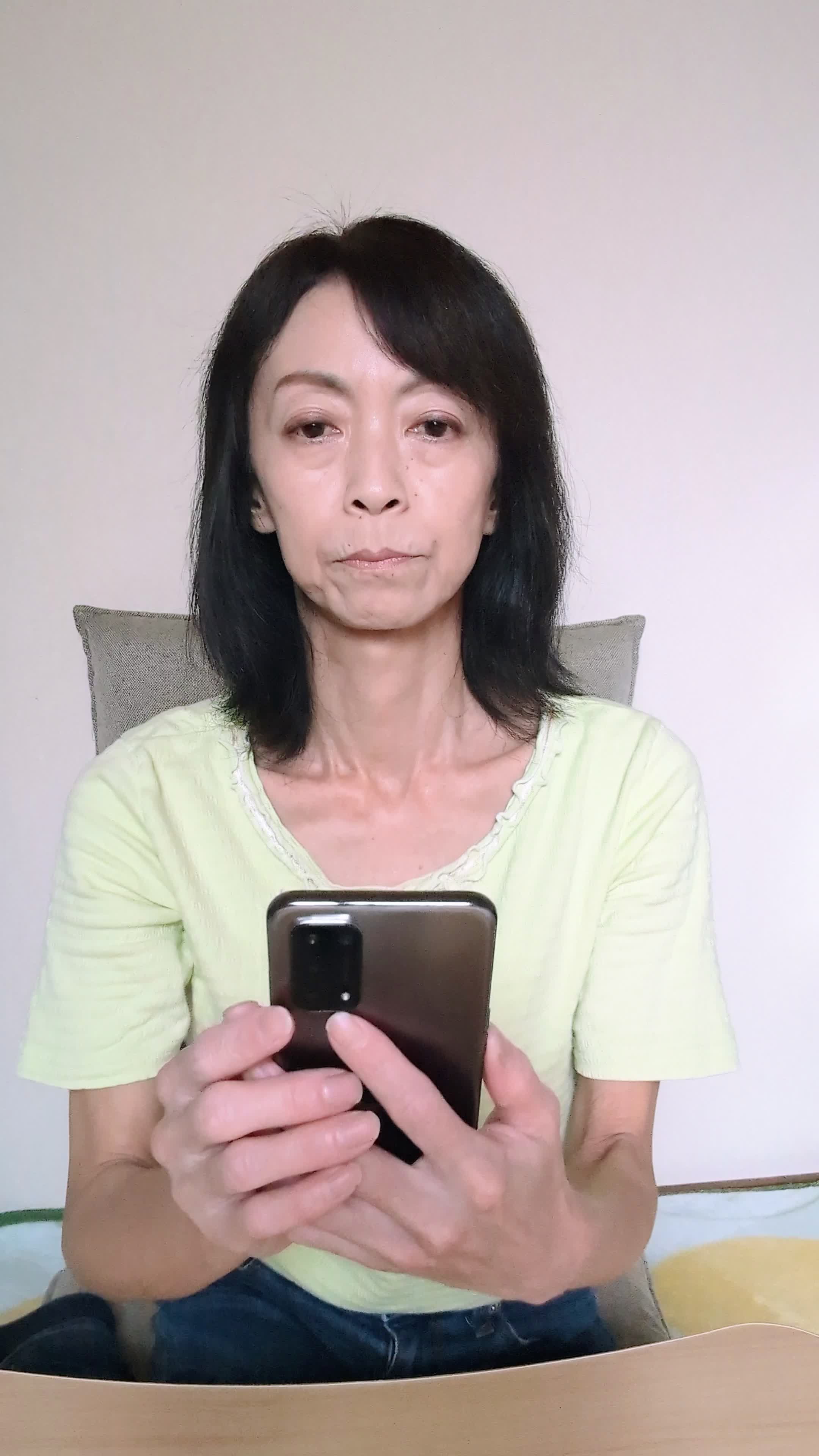 テーブルでスマホを操作し、「注文履歴を見て再注文を考える」真剣な表情