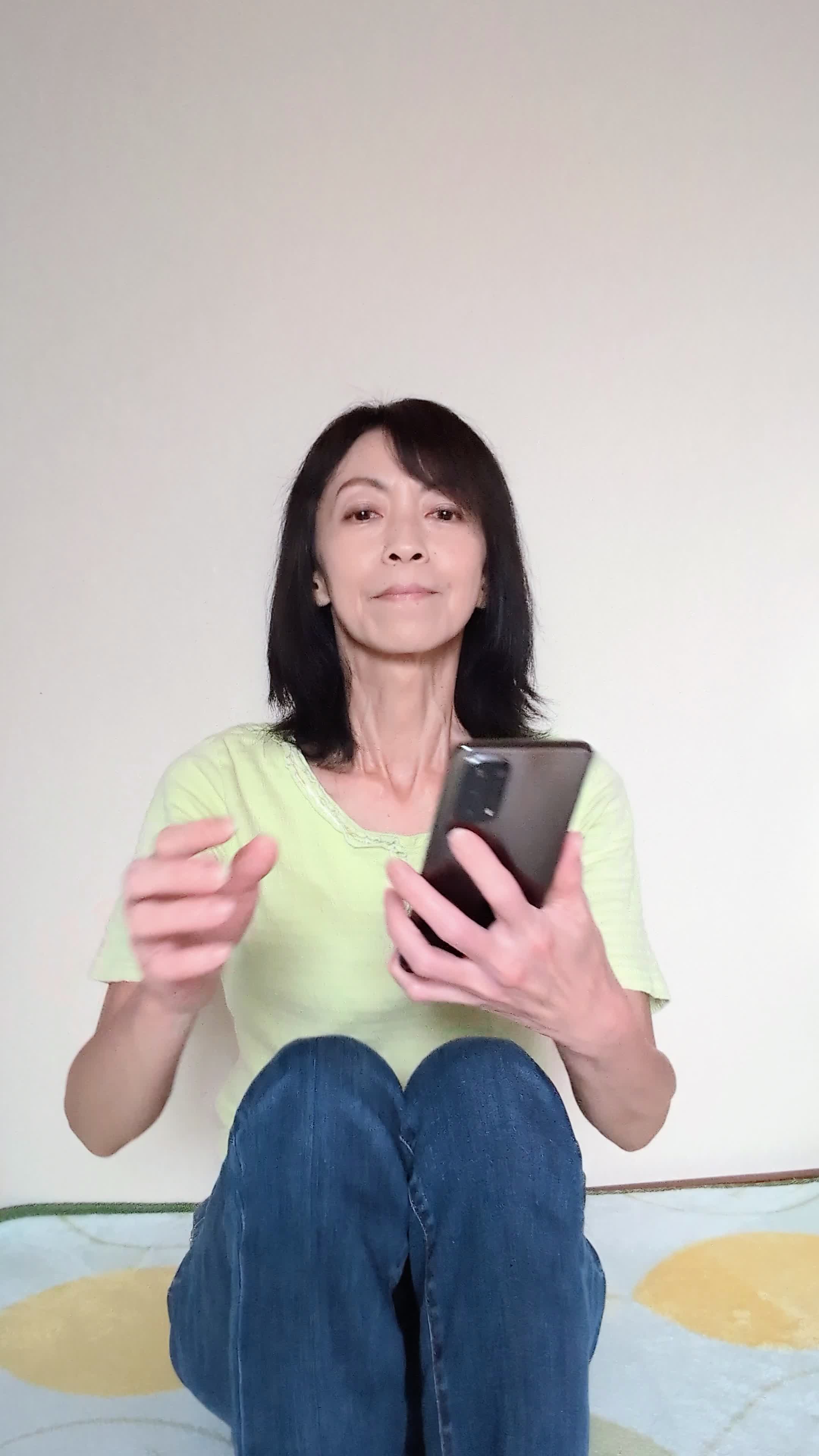 床に座り込み、スマホで商品画像を見て「このデザイン素敵！」と微笑む仕草