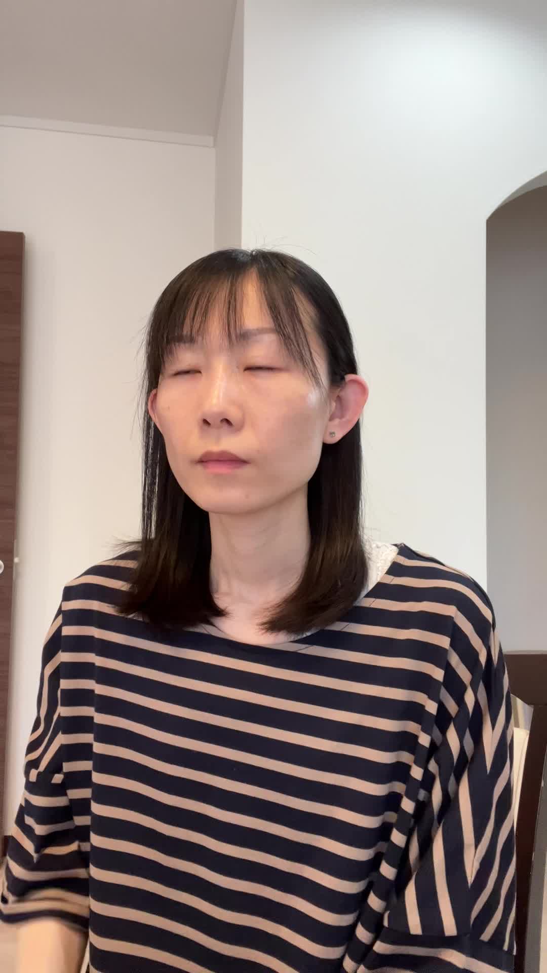 椅子に座り、手でこめかみを押さえながら「最近ずっと頭が重い」と困った表情