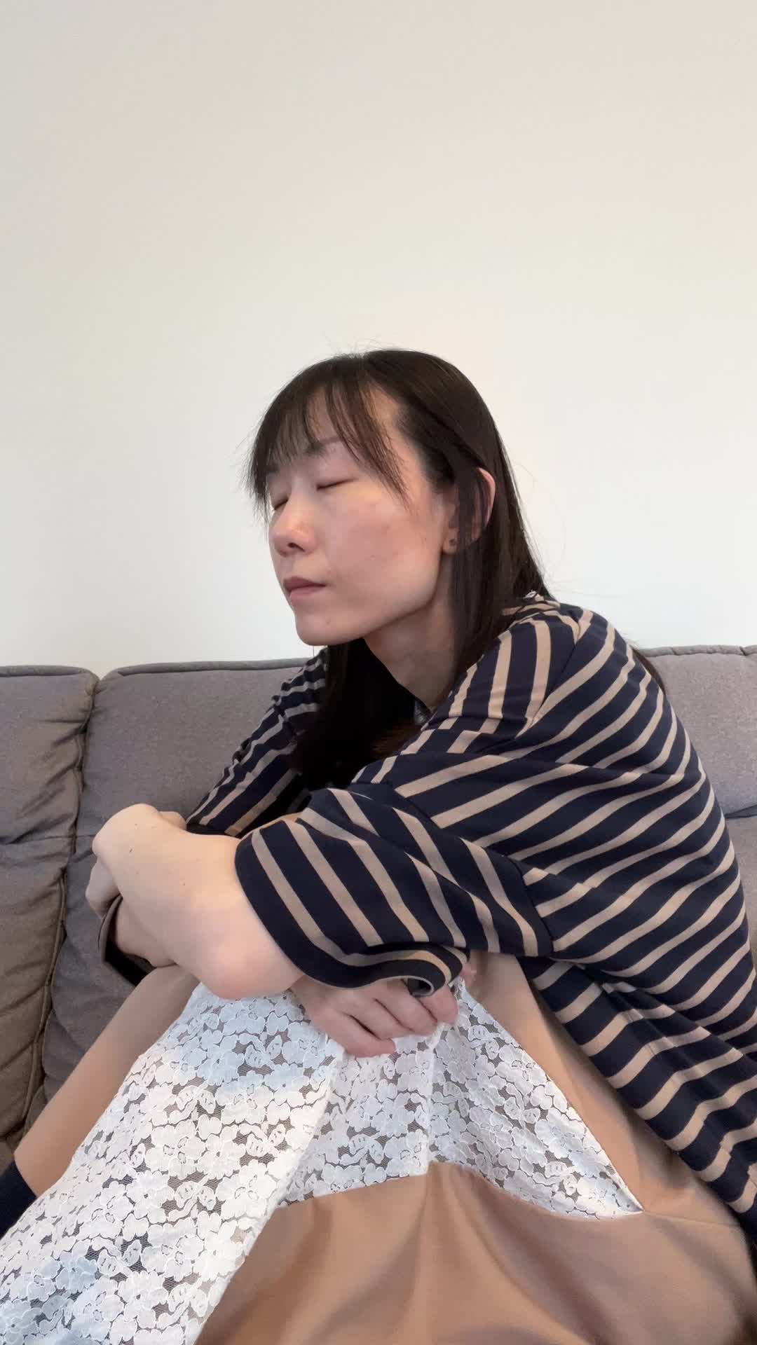 ソファで膝を抱え、「疲れやすくて何もする気が起きない」とため息をつく様子