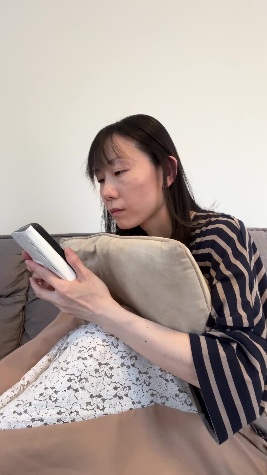 ソファでクッションを抱え、「疲労感が抜けない原因を調べている」集中した表情