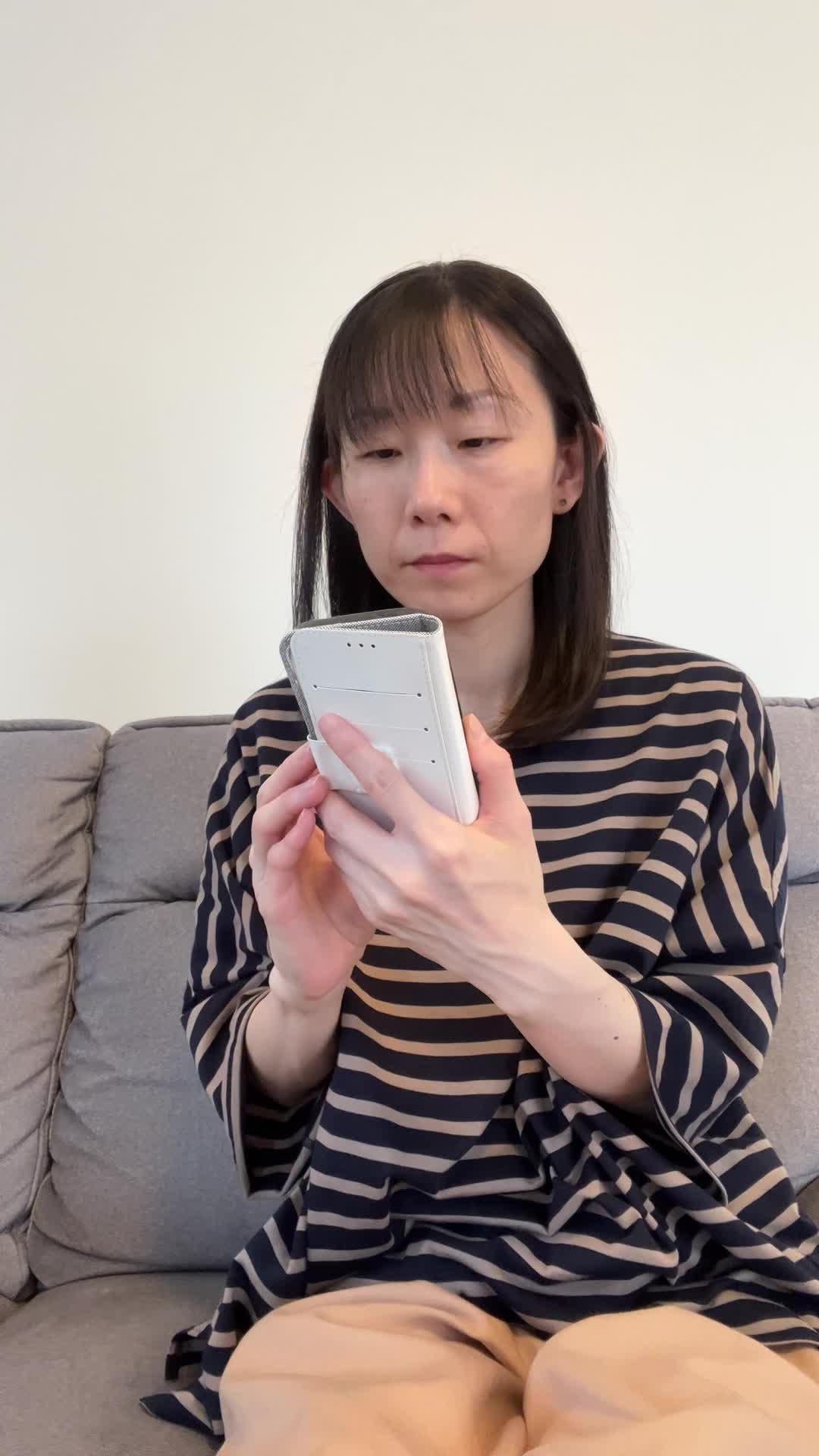 ソファでスマホを眺めながら、「健康ドリンクの口コミを見て少し希望を感じる」表情