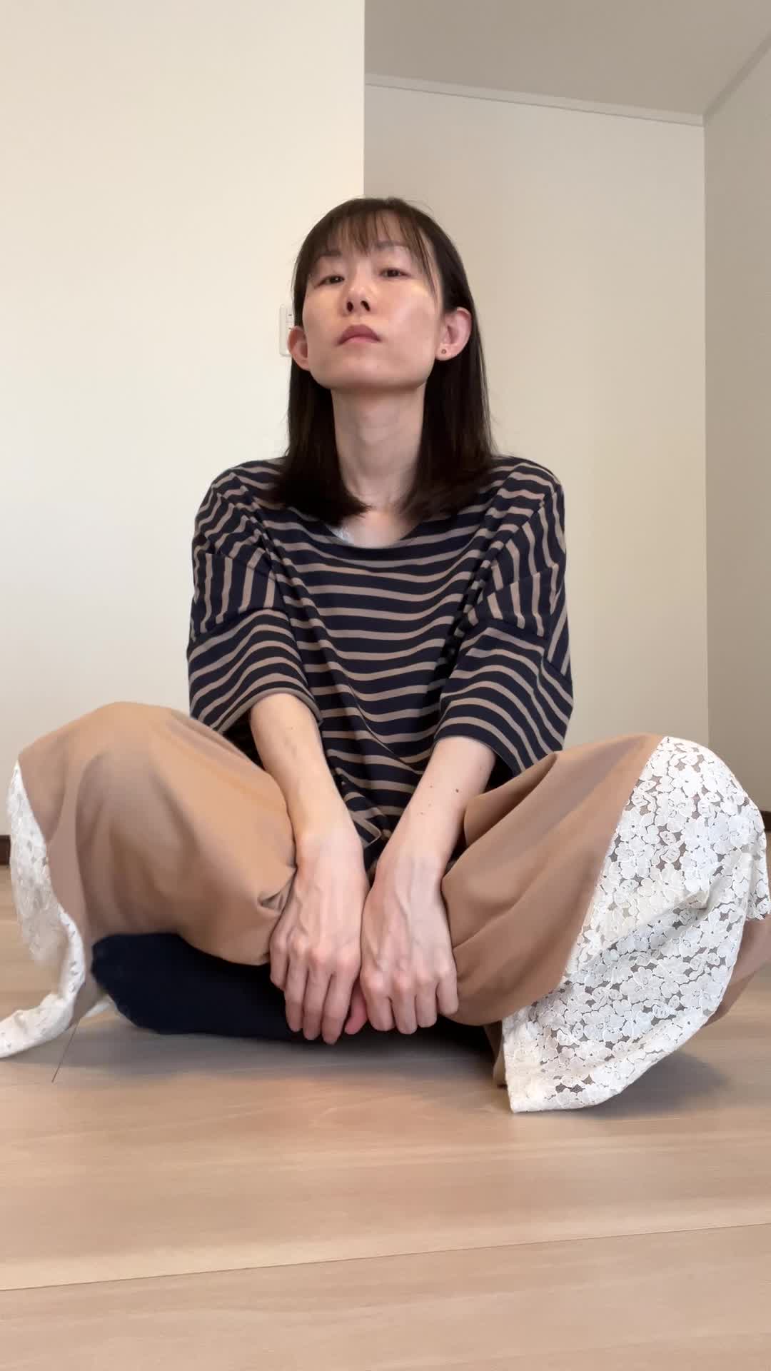 床に膝を崩して座り、「体が重いのは食生活が原因かもしれない」と考え込む姿