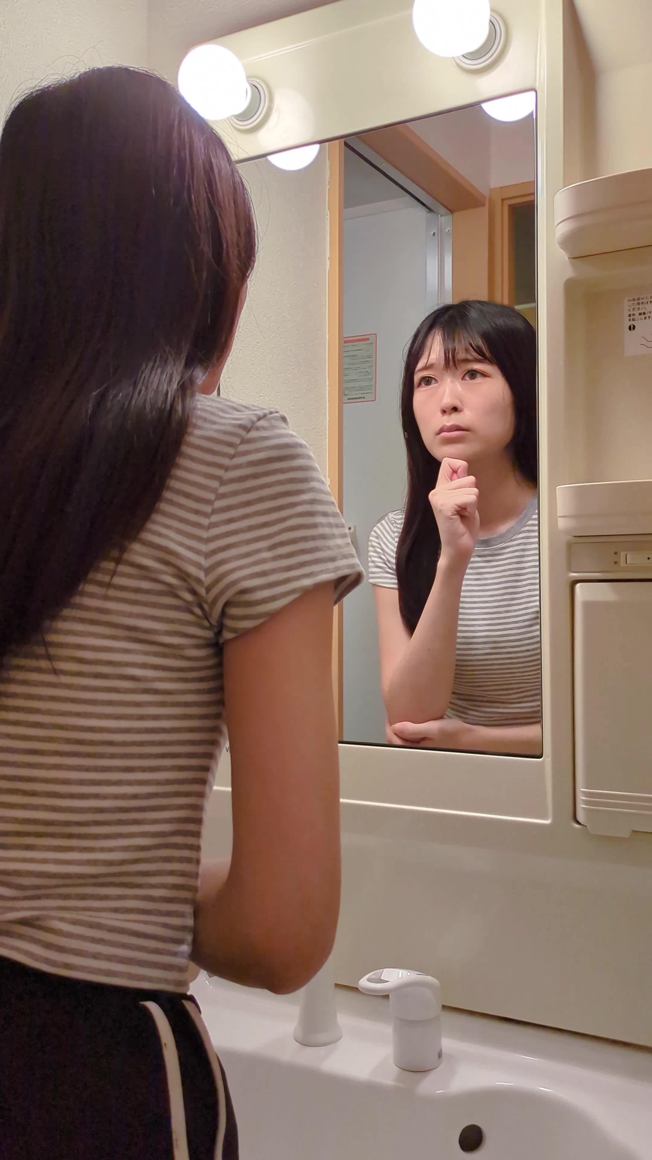 鏡を覗き込みながら「どうやったらこうなるの？」と考えるポーズ