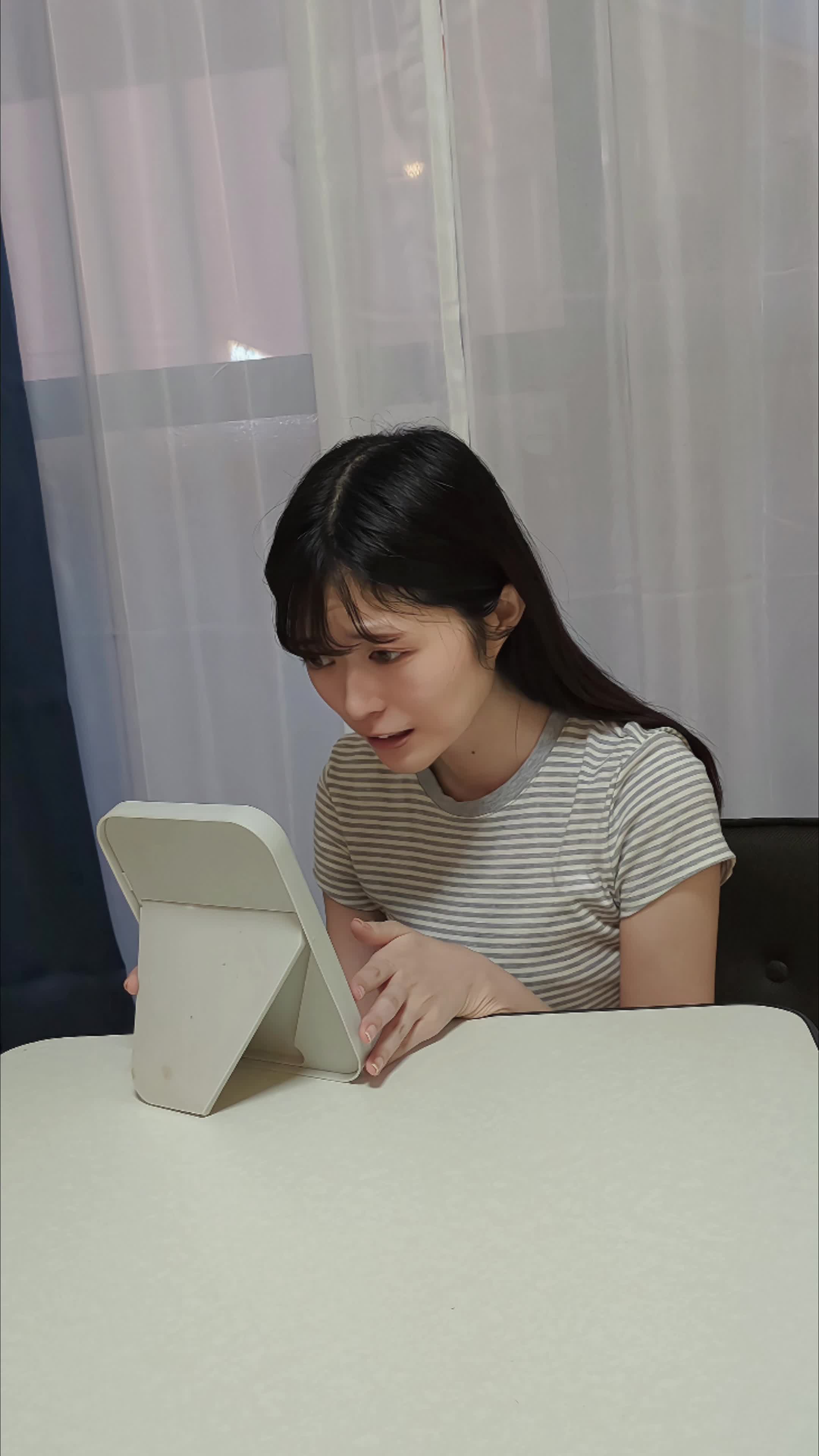 テーブルに手鏡を置いて、「白くなるかな…？」と不安げに覗き込む動作
