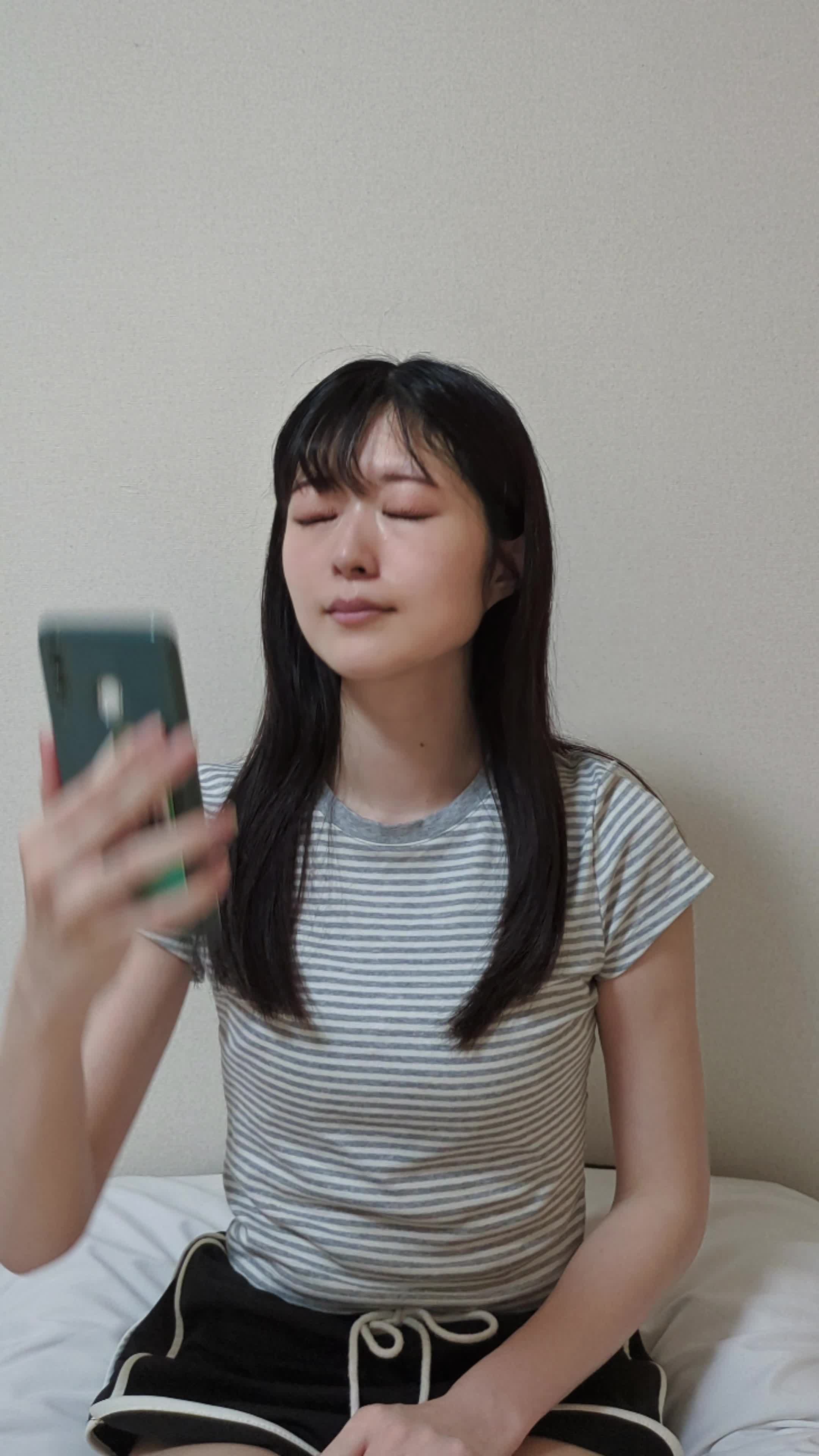 スマホで自撮りしながら、歯の色を確認して悩むような表情を浮かべる