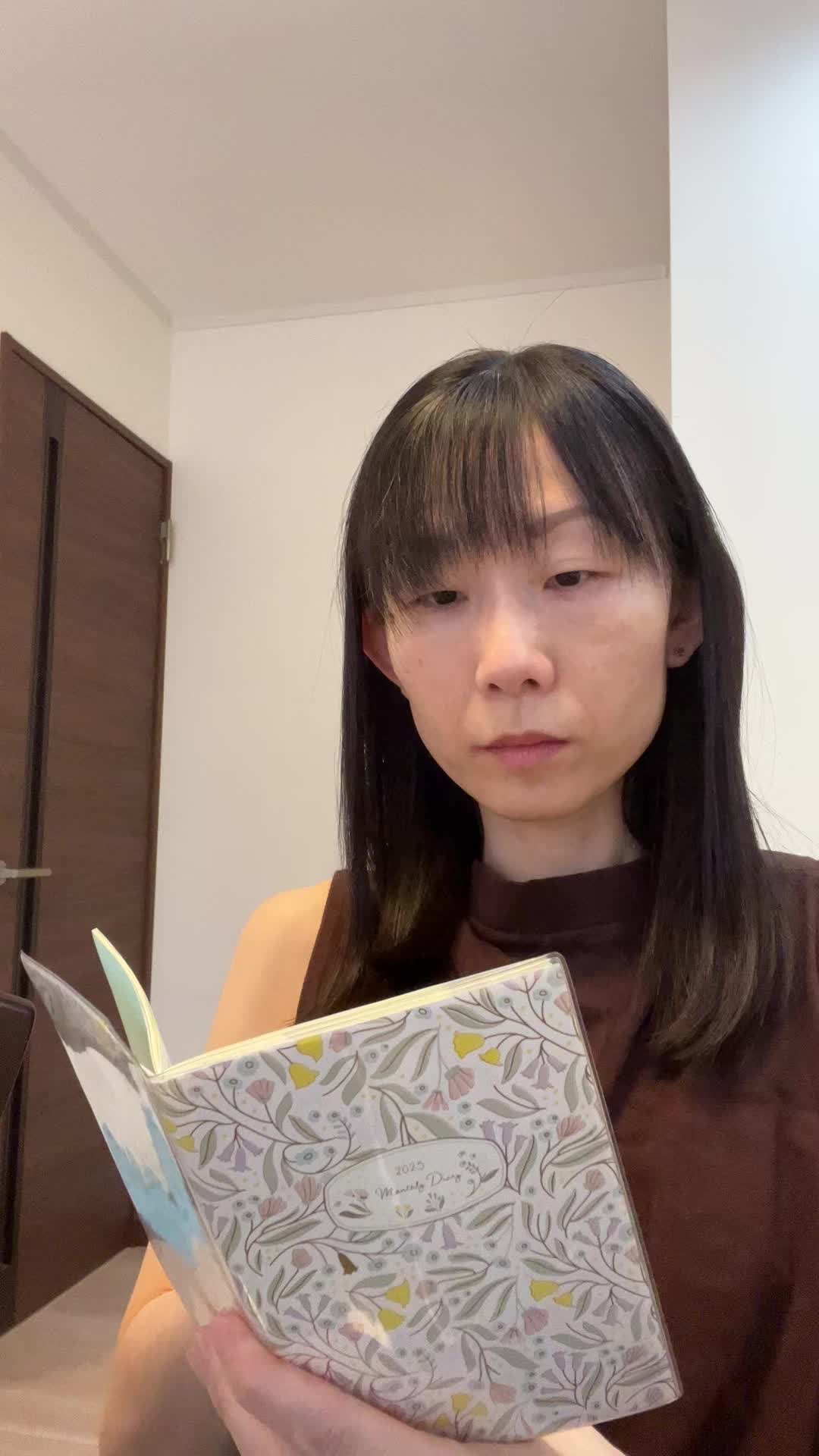 手帳を指差しながら、「これが目標だ！」という決意を表す動作
