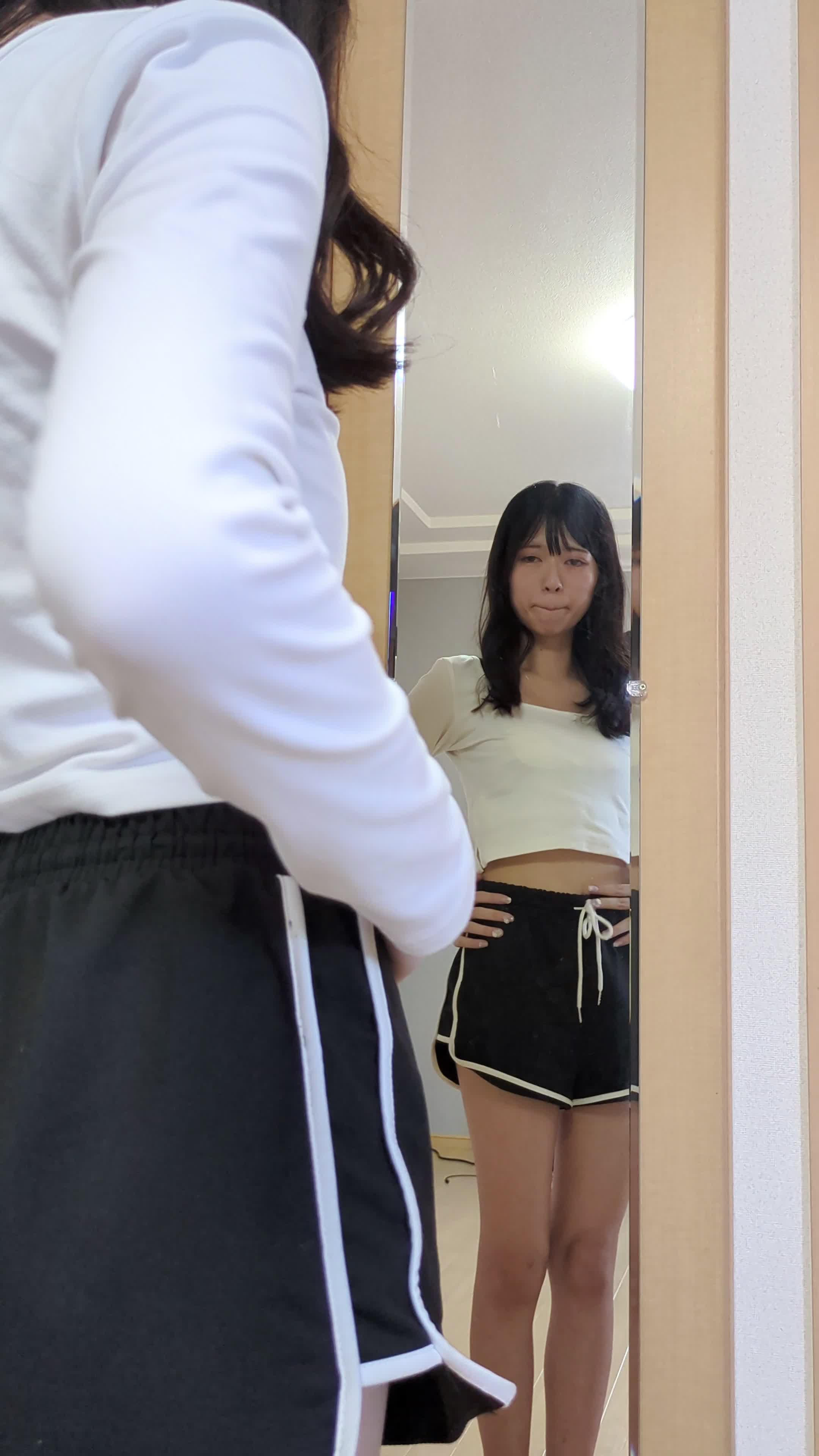 鏡に映る自分を見つめながら軽くウエストラインを確認する仕草をする