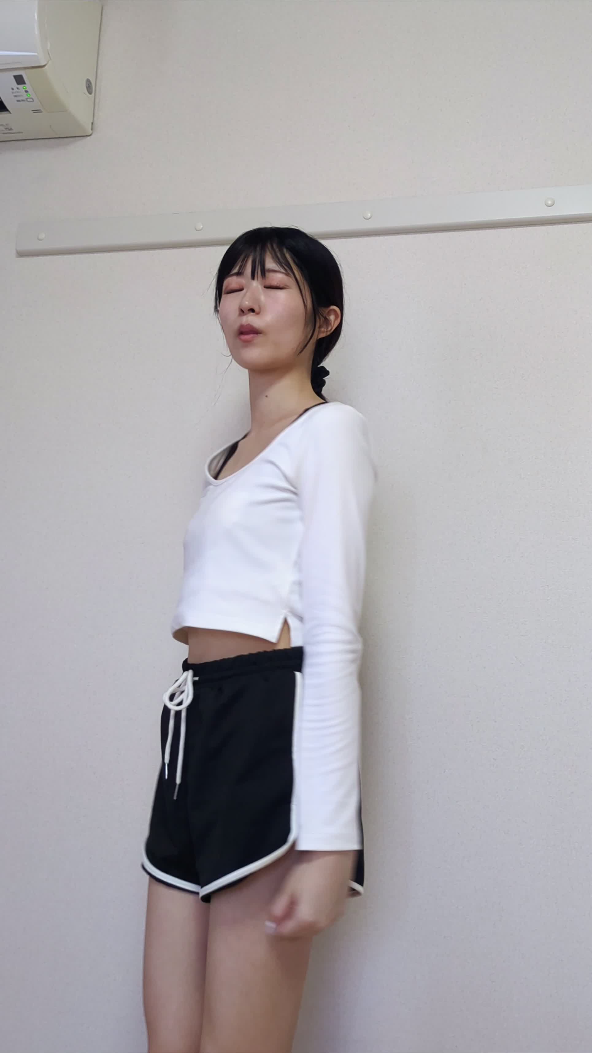 リビングで立ったまま軽く体をひねるストレッチをしている