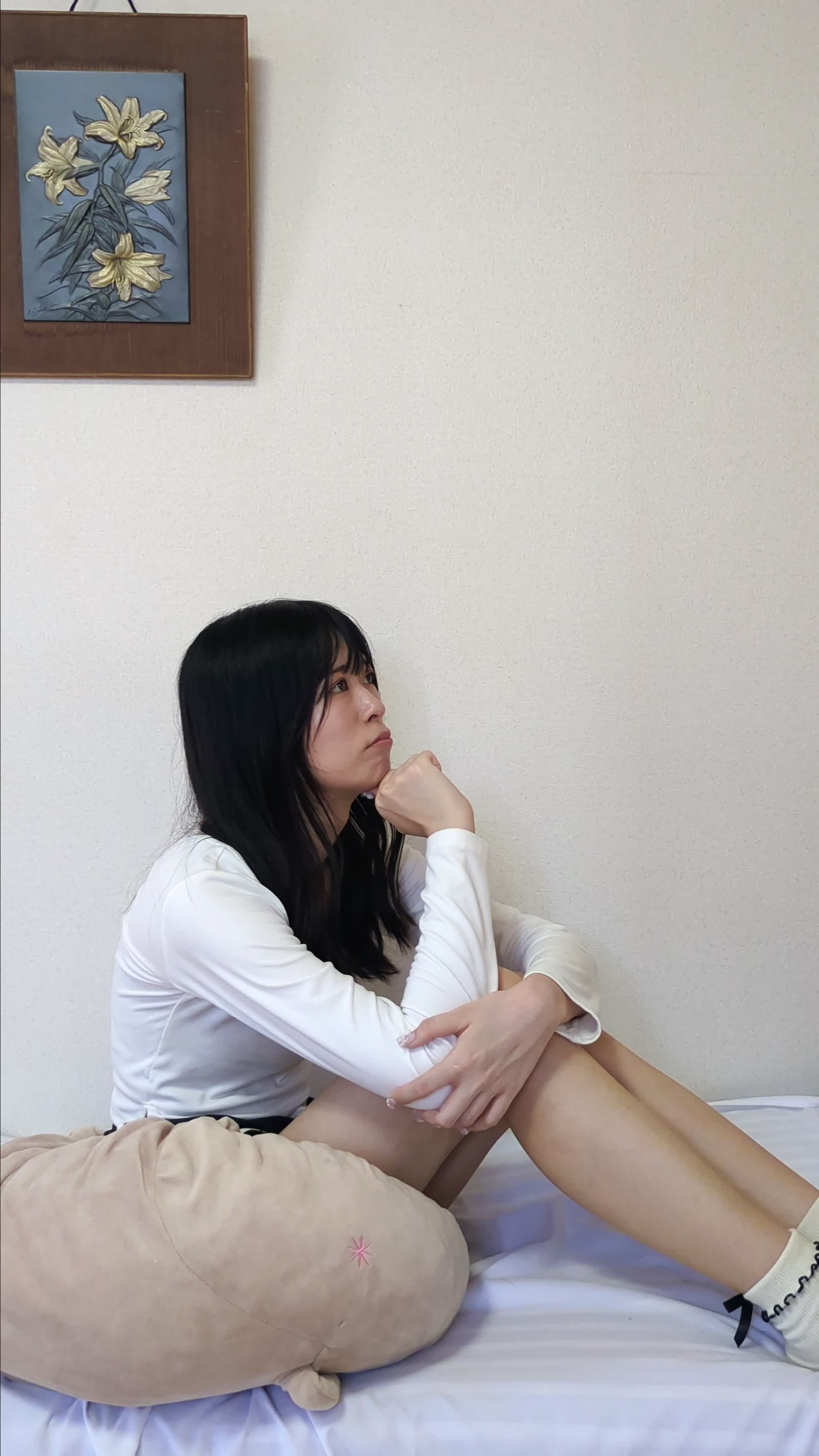 ソファで膝を抱えて座り、少し悩んだ表情を浮かべている
