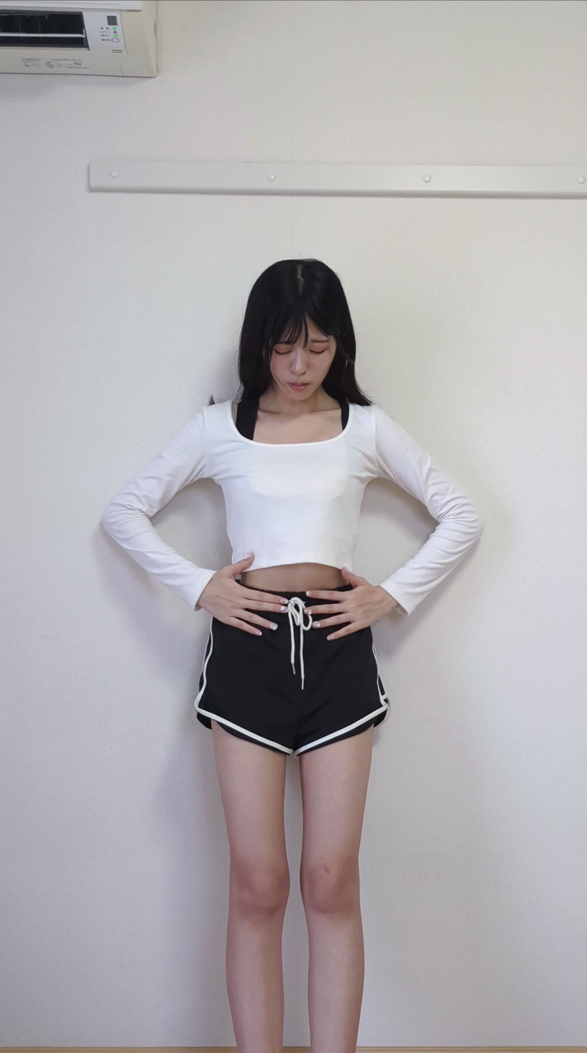 壁にもたれ、手で軽くウエストを押さえながら考えている表情をする