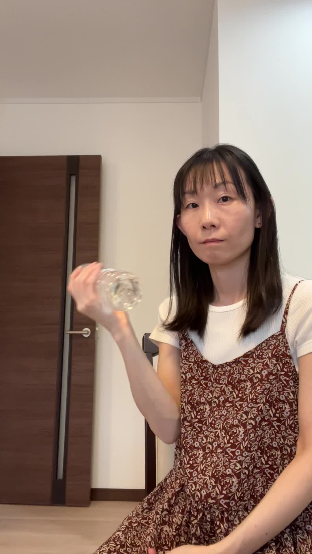 椅子に座り、ペットボトルをダンベル代わりにして軽く腕を曲げる仕草