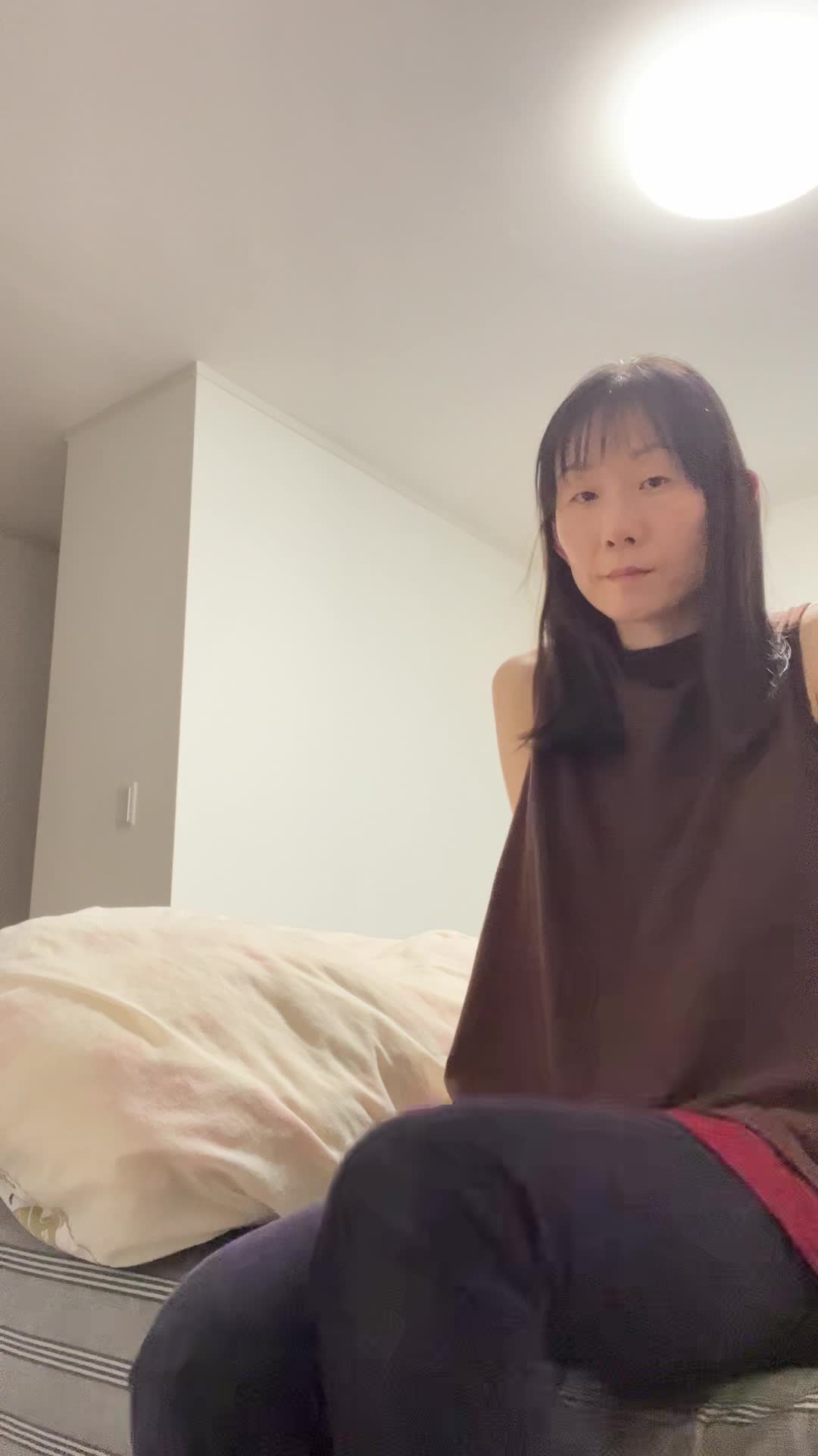 ベッドの端で軽く足を振り上げ、「キックの練習！」と自分に笑いかける仕草