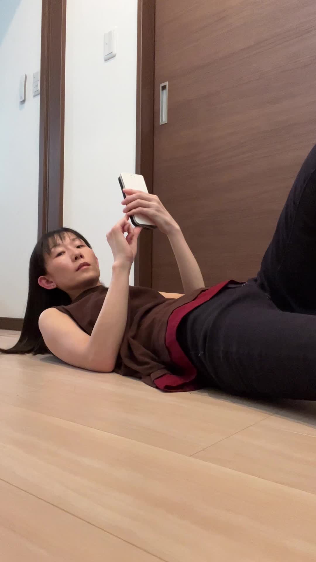 床に寝転び、仰向けになって「1分間プランク」のタイマーをセットする動作