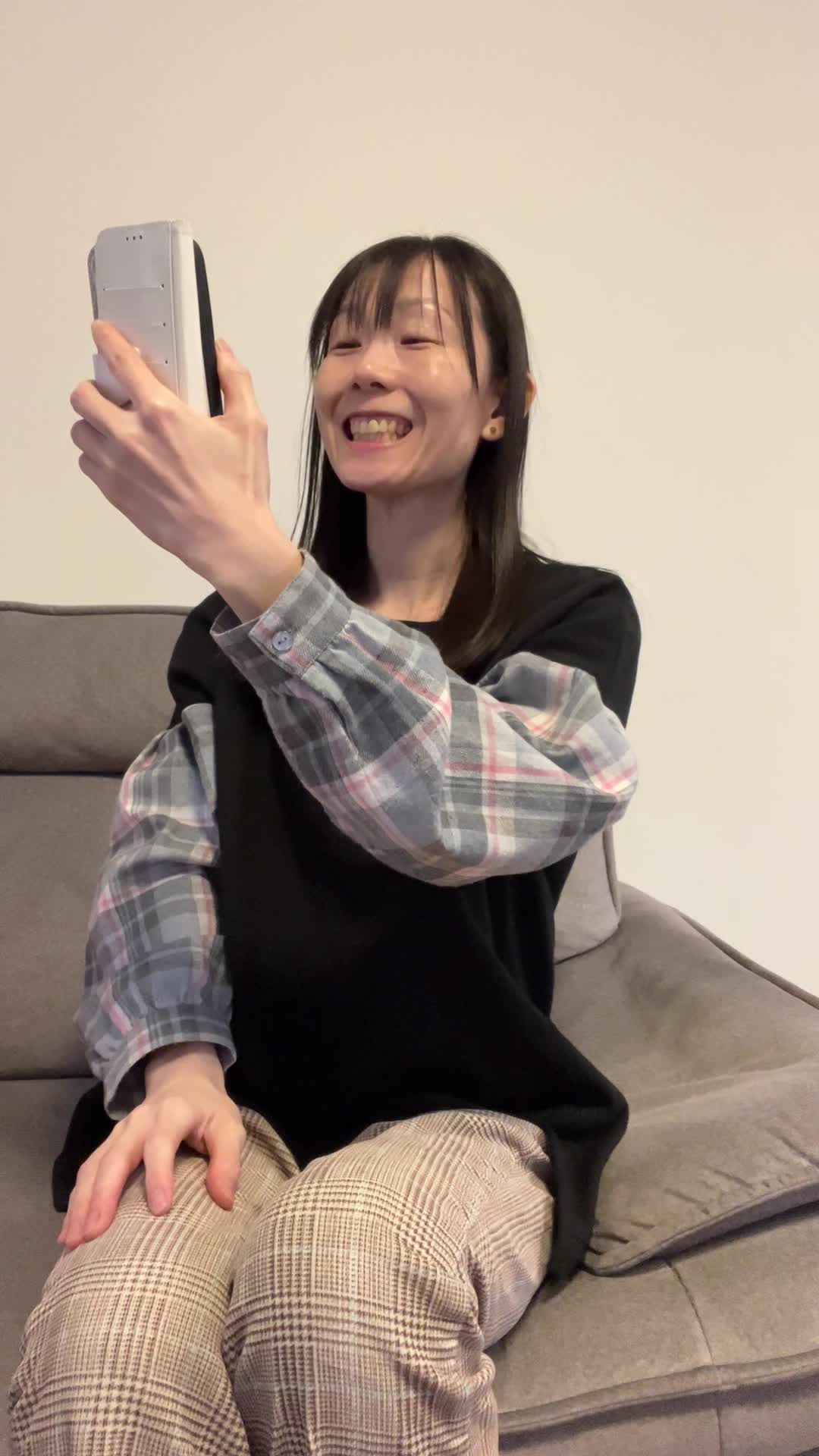 ソファでスマホを見ながら笑顔を作り、歯を確認して少し驚く仕草