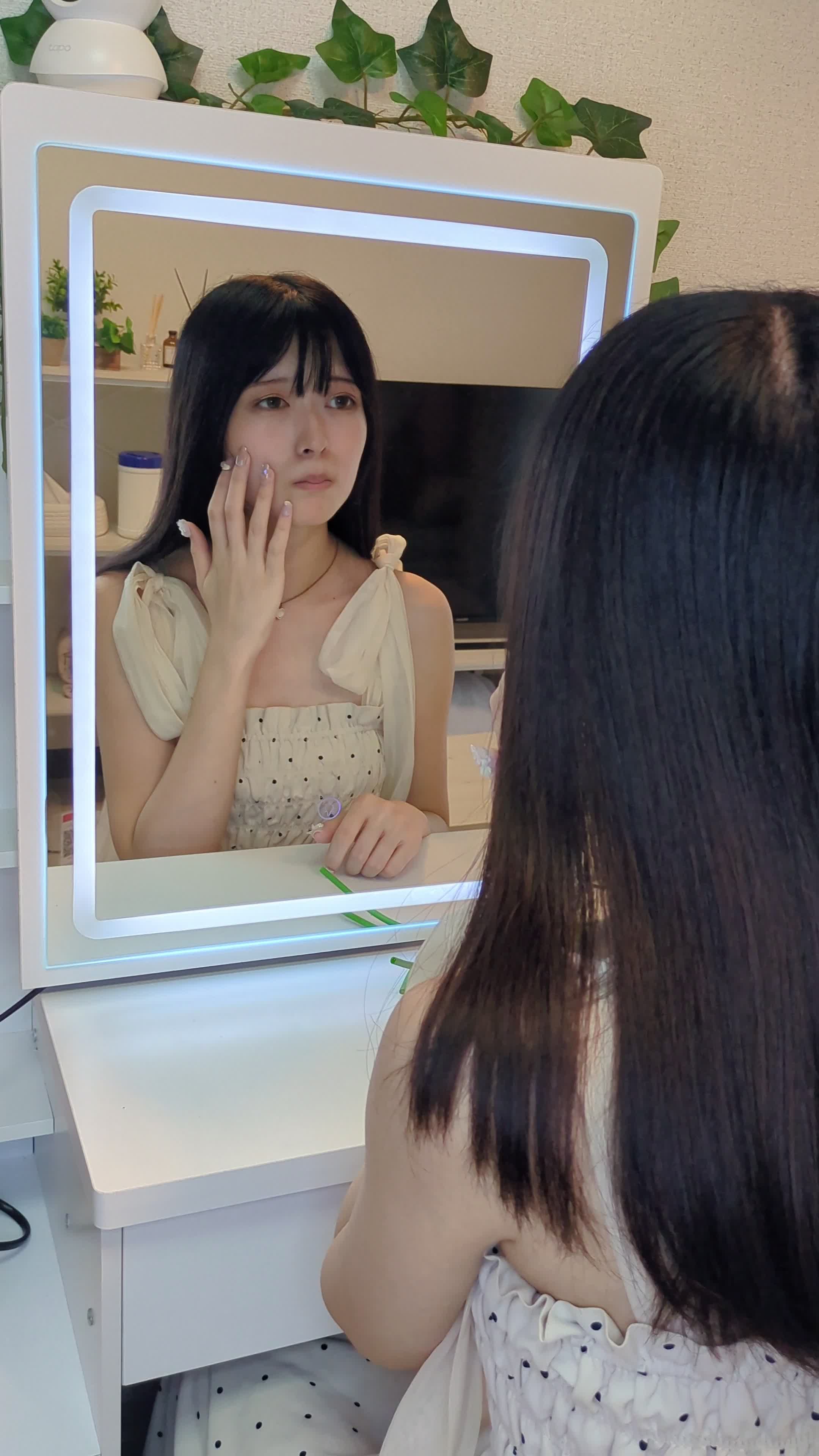 鏡の前で顔を軽く触りながら肌の状態を確認している