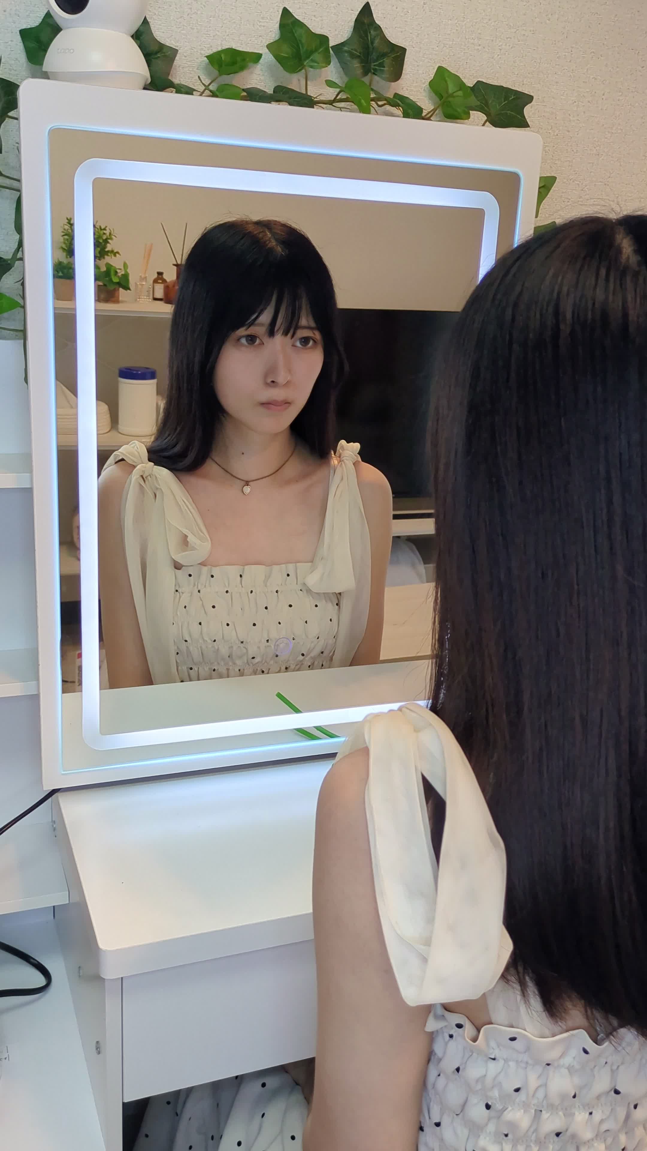 鏡をじっと見つめ、手で顔をかき上げる動作をする