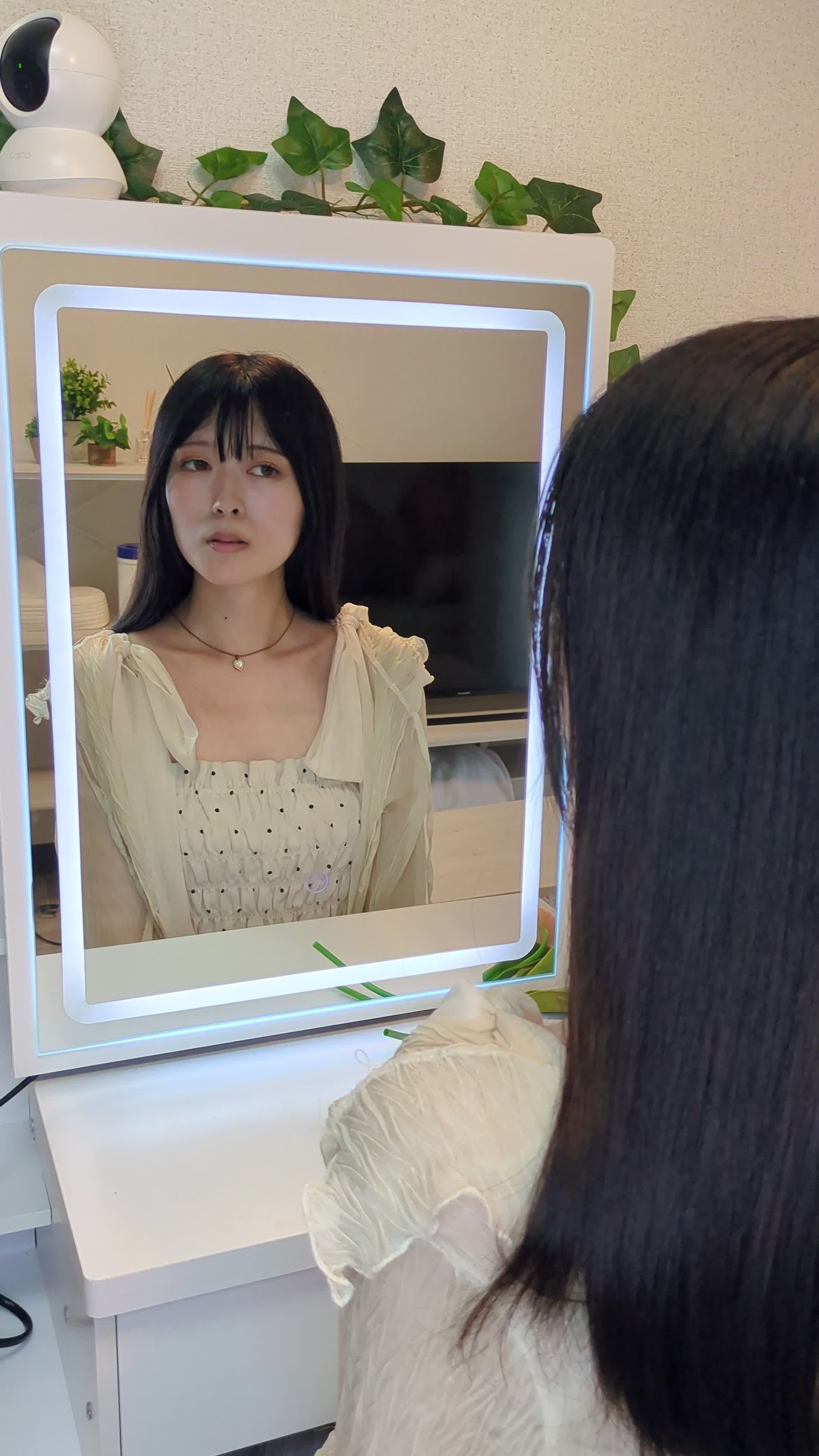 鏡に向かって首を軽く動かしながら横顔をチェックする仕草をする