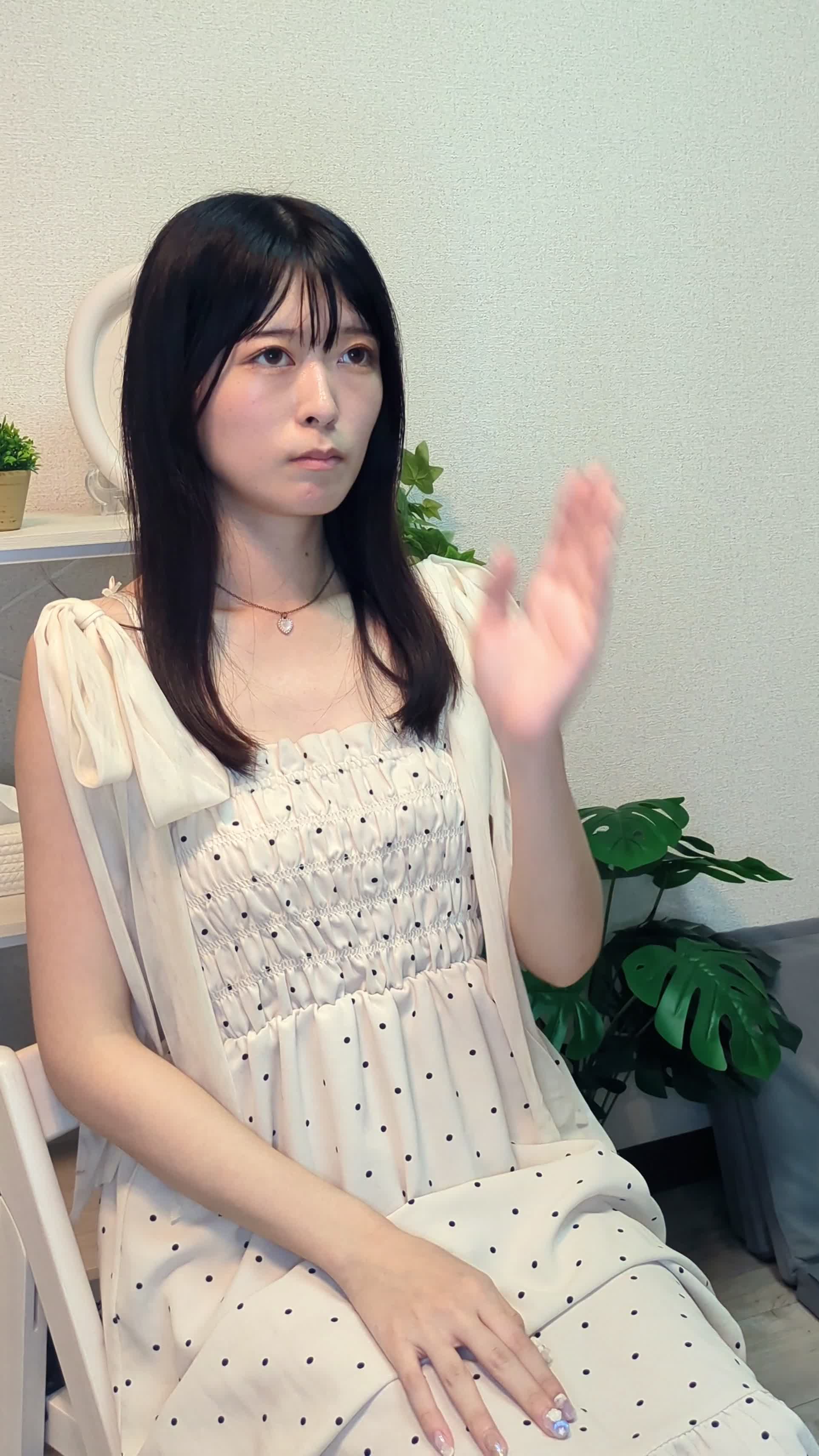 椅子に座り、片手で頬を押さえながらじっと考えている表情を見せる