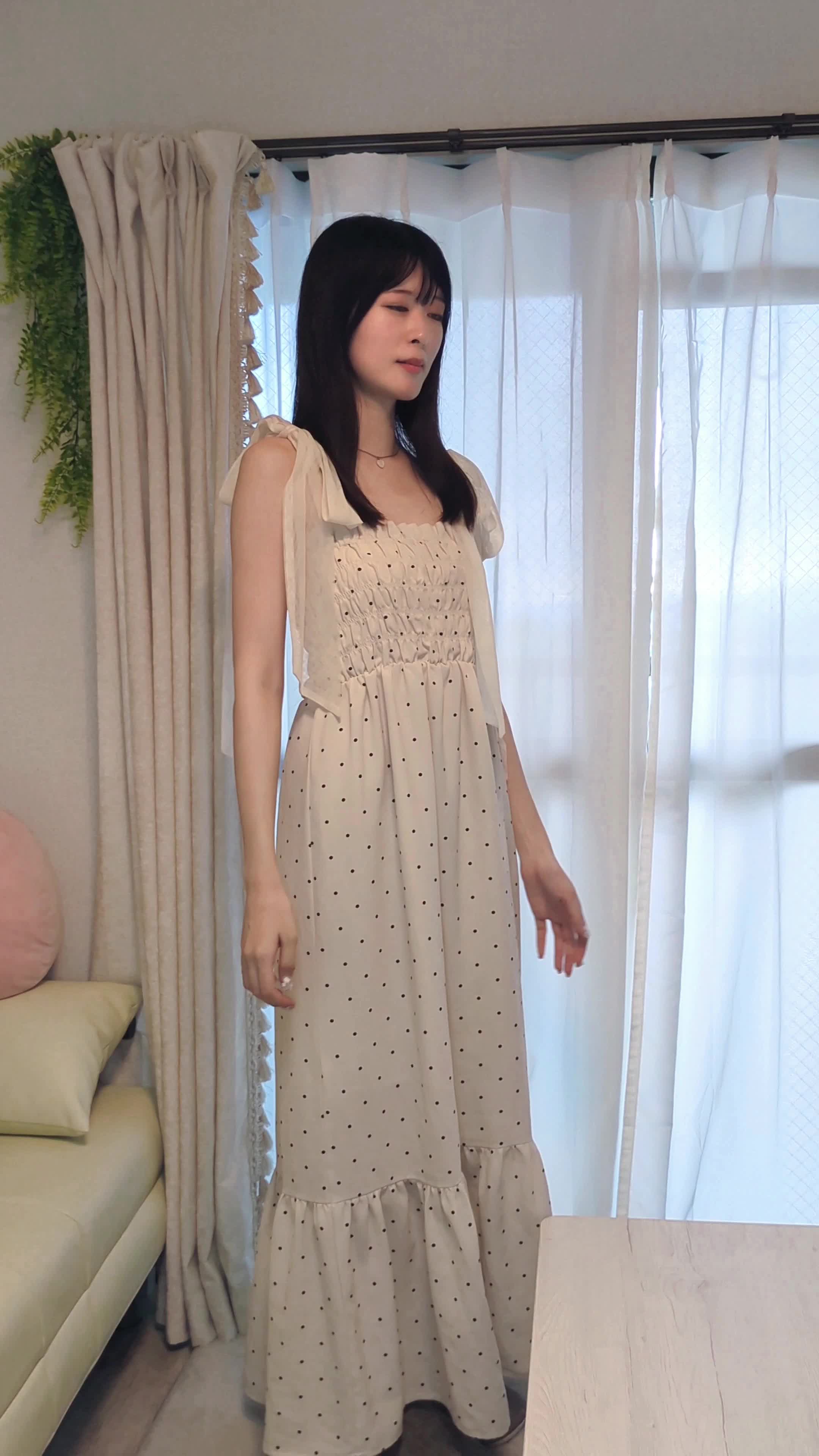 リビングで軽く背伸びをしながら、両手を頬に当てるリラックスした姿
