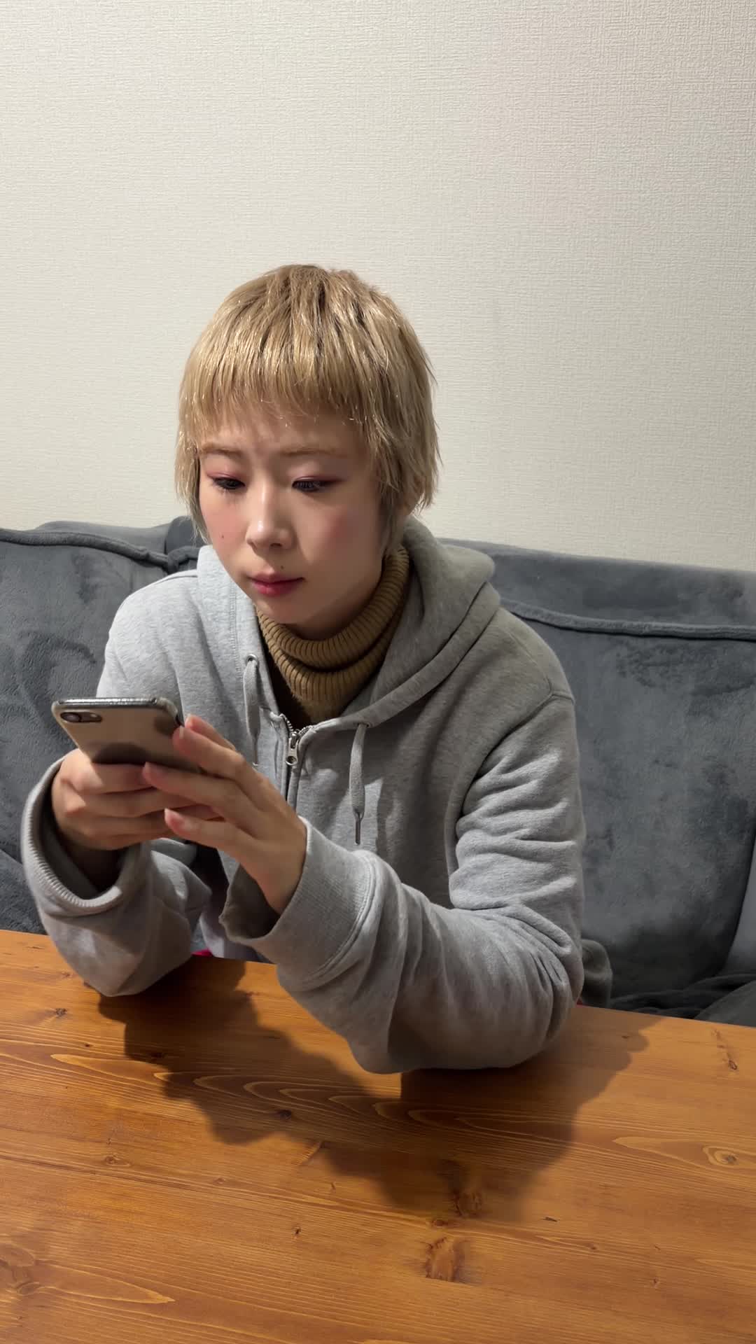 ソファに座り、スマホで「車 査定 高く売る方法」と検索している仕草