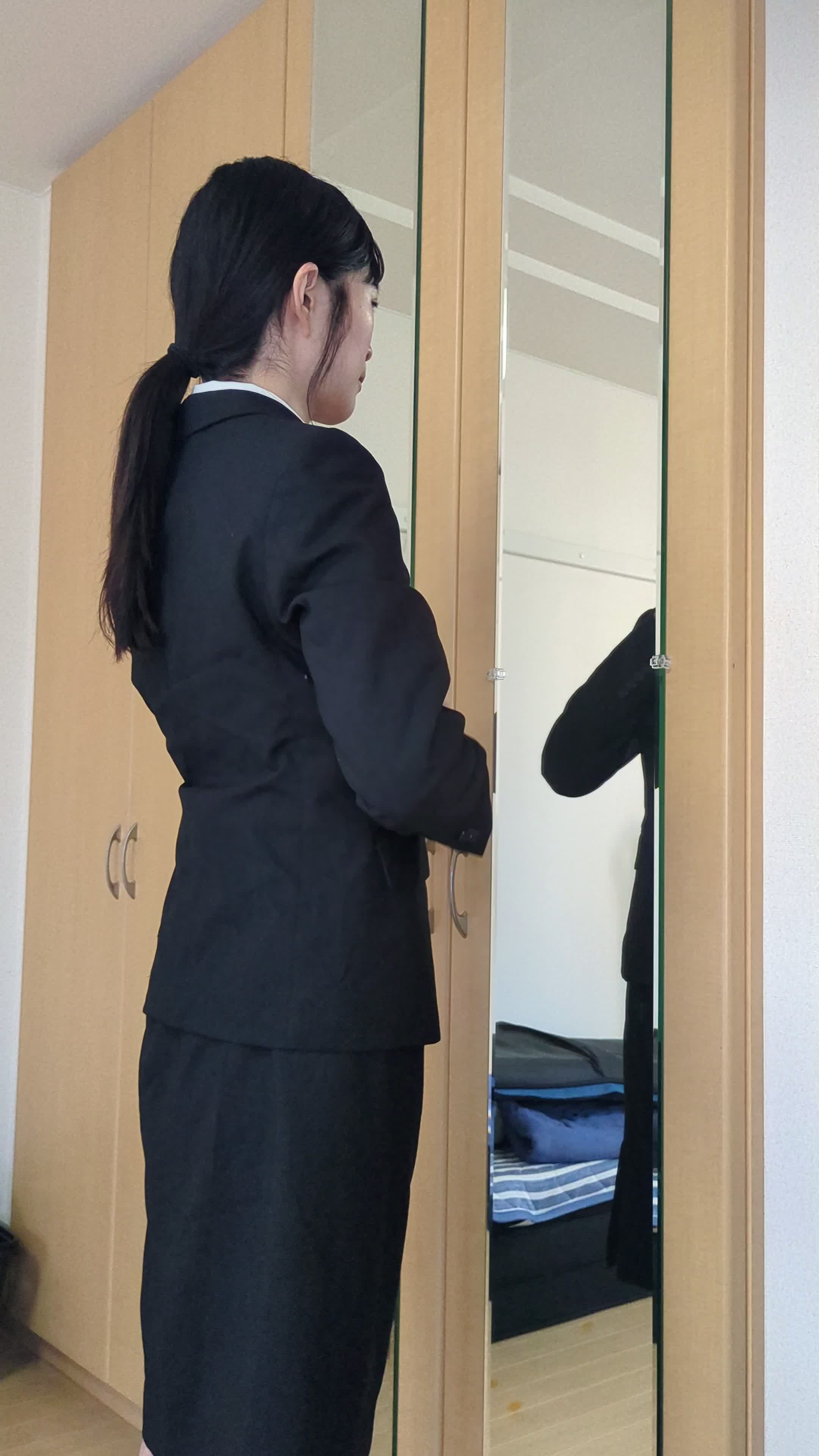 スーツを試着し、鏡の前で身だしなみを整えている