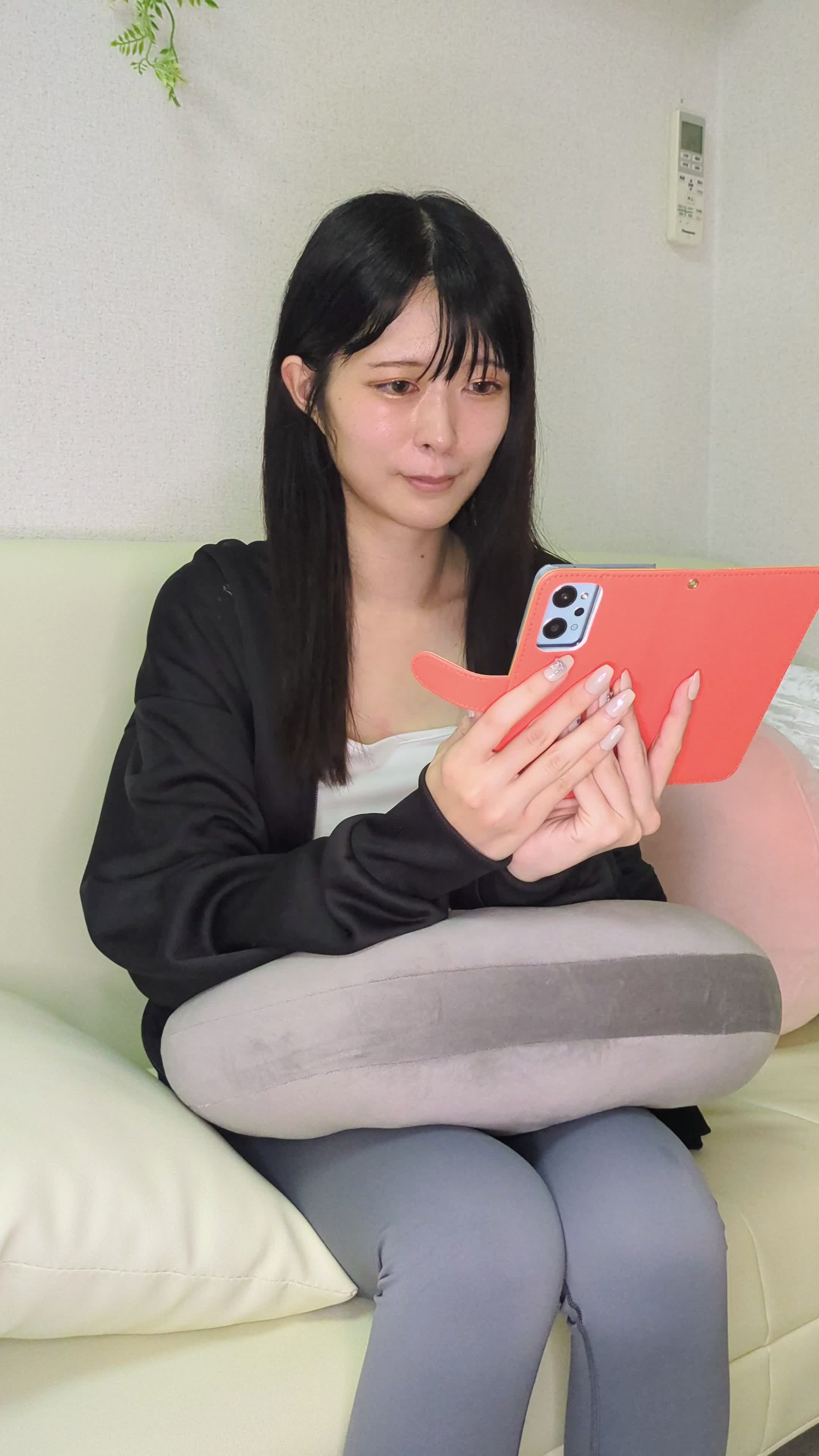 ソファに座り、企業からのメールを読みながら微笑む