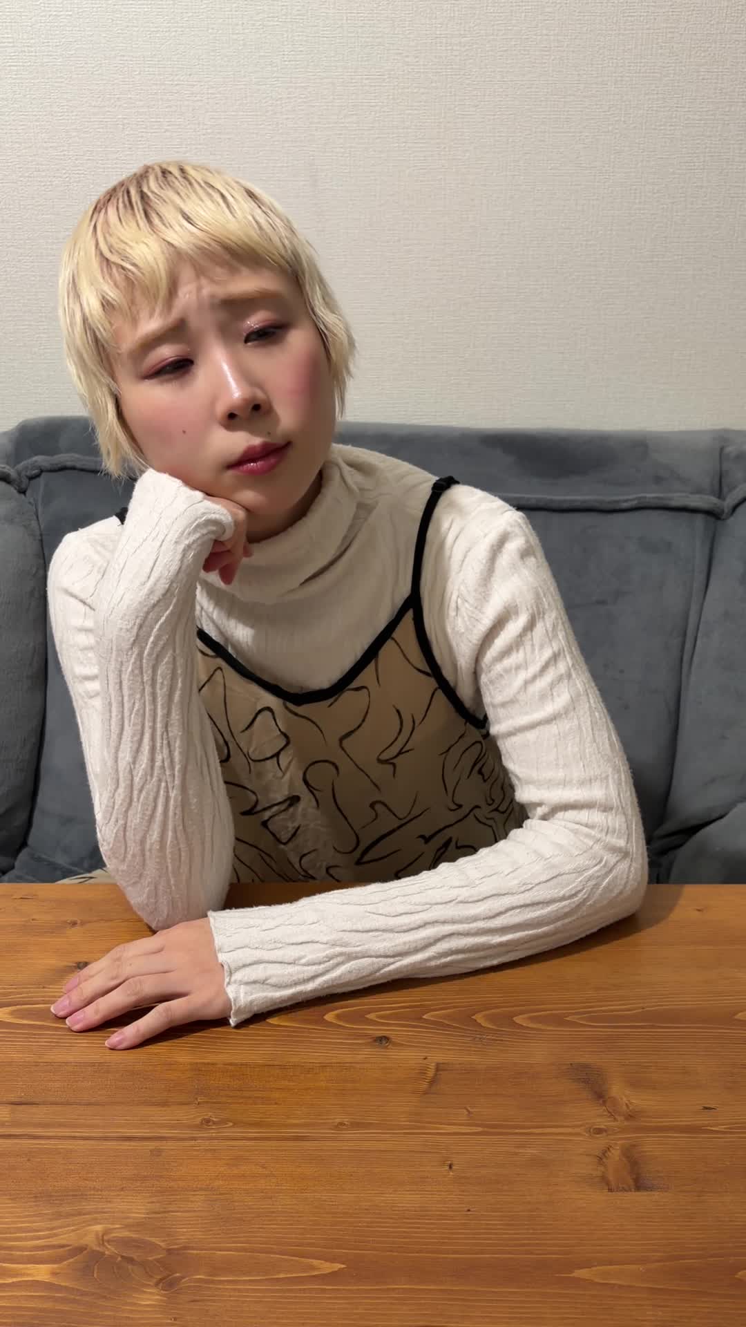 テーブルに肘をつき、「今始めないと後悔しそう」と悩む様子