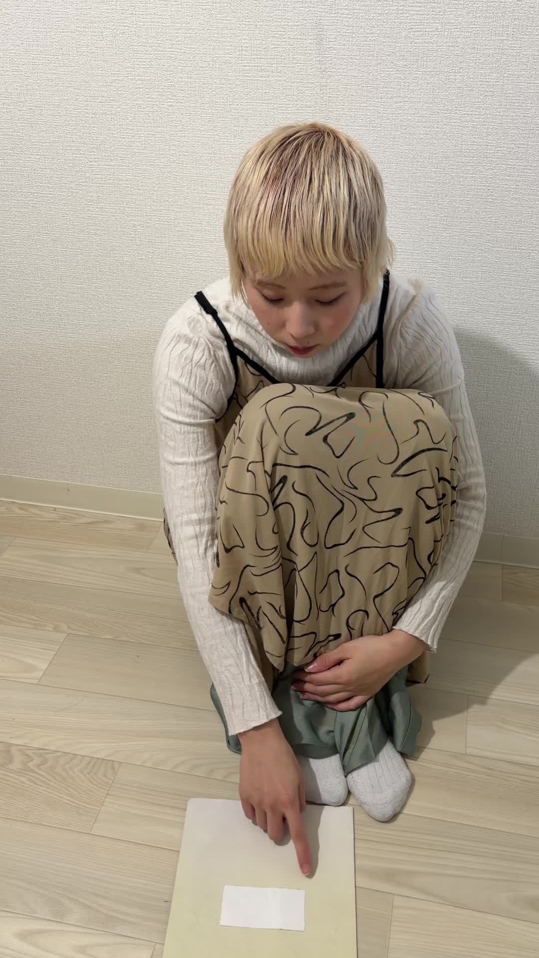 床に座り込み、カレンダーを指差しながら「この日なら行ける！」と考える動作