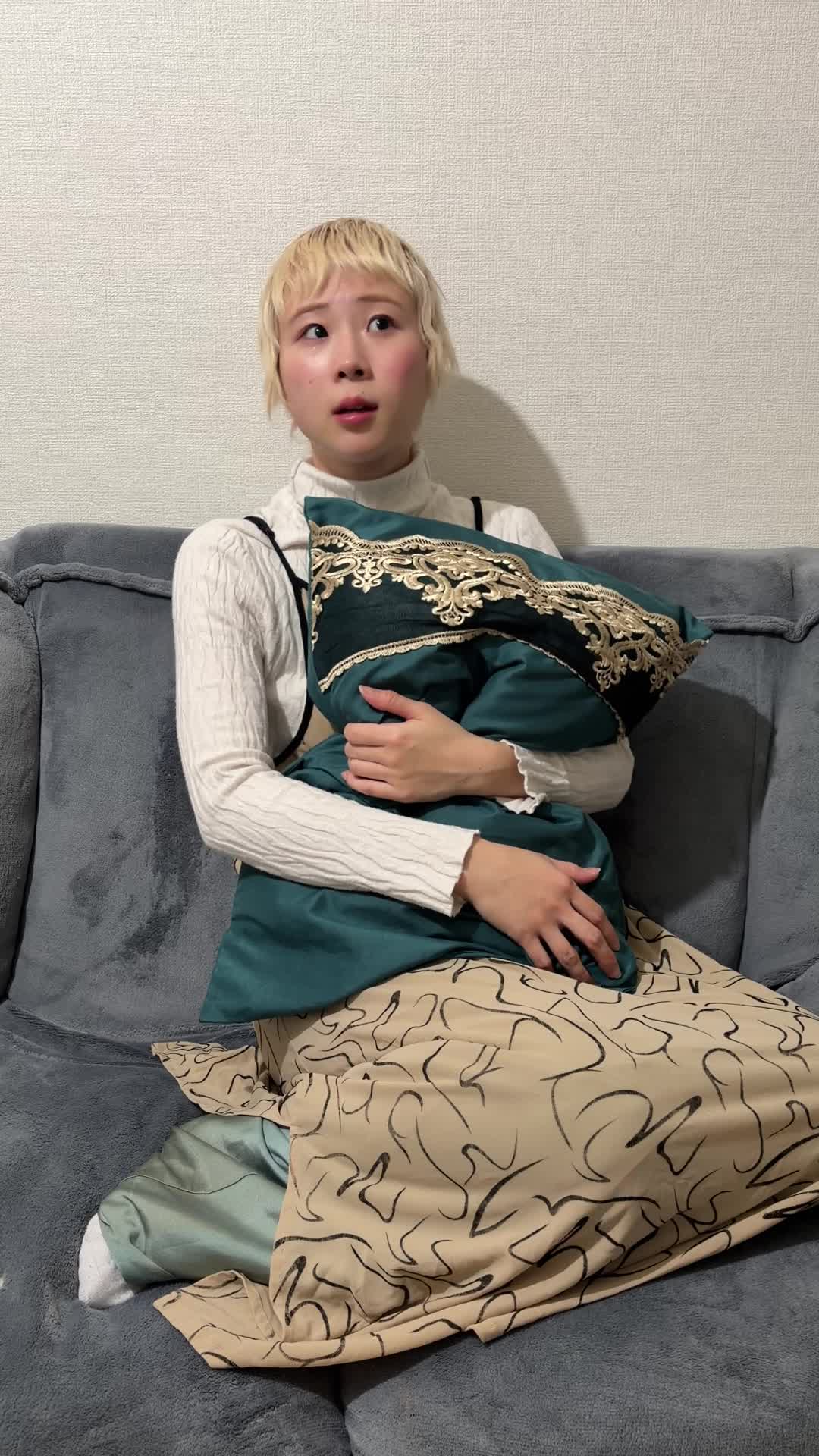 ソファでクッションを抱きしめ、「迷ってる場合じゃない！」と決断する仕草