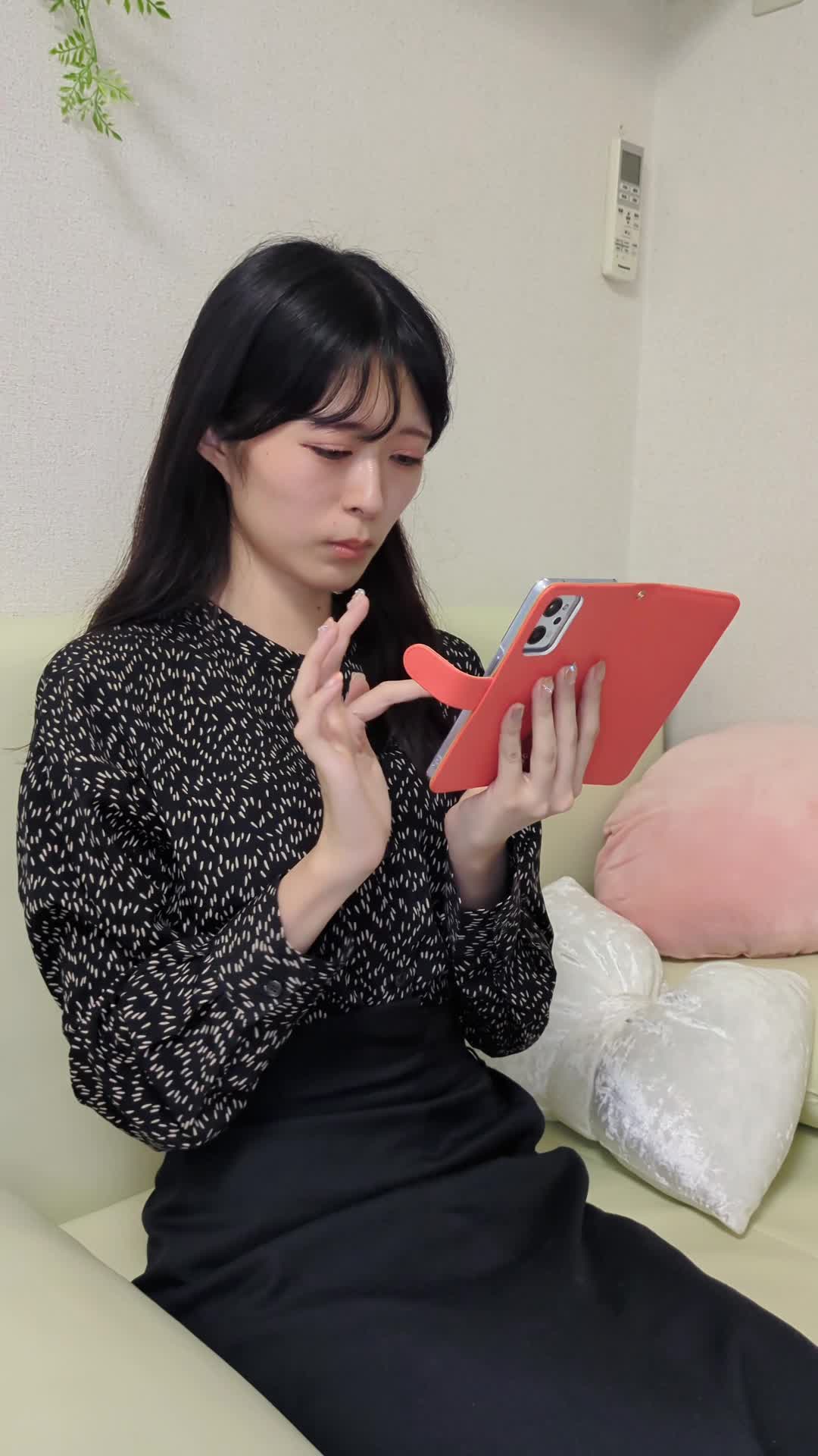 ソファに座り、スマホで「車 査定 高く売る方法」と検索している仕草
