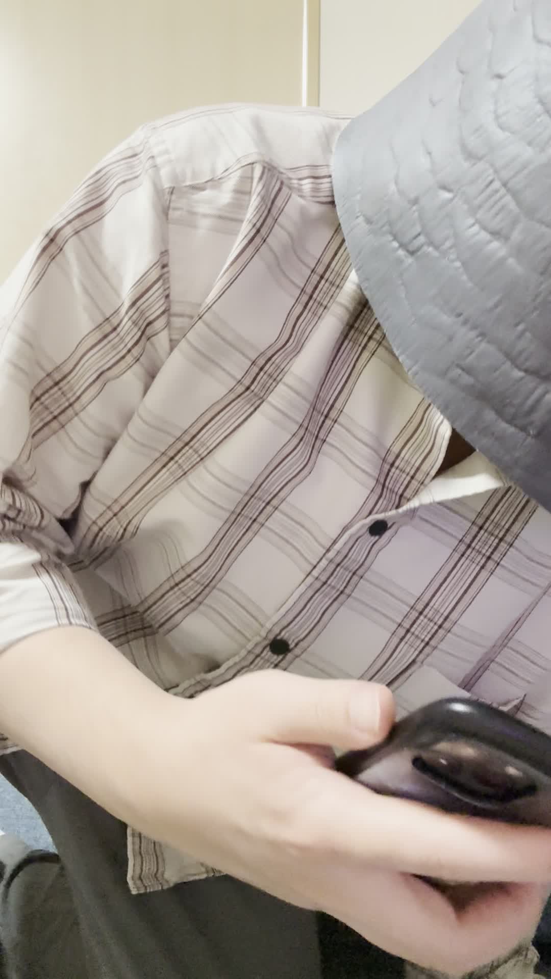 椅子に座り、スマホでカートの中身を確認しながら「これ全部買おうかな？」と悩む表情