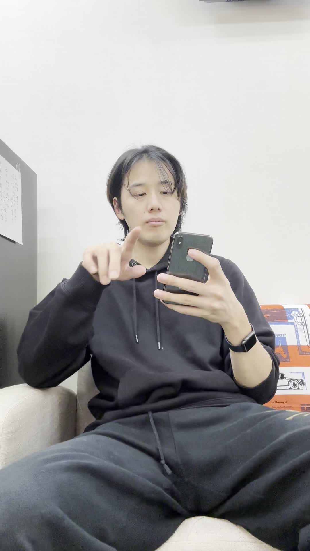 床に座り込み、スマホで「保険の口コミ」を見ながら少し安心した表情を浮かべる