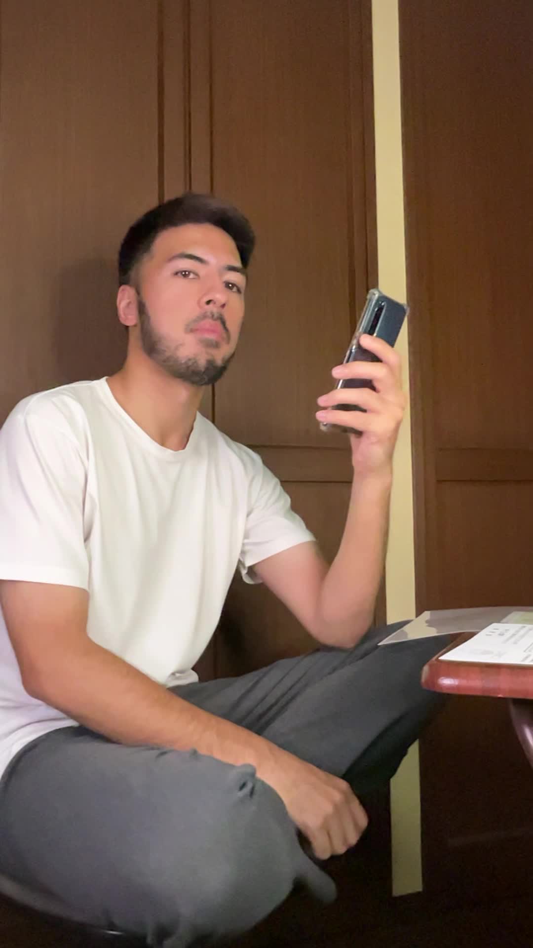 床に座り込み、スマホで「保険の口コミ」を見ながら少し安心した表情を浮かべる