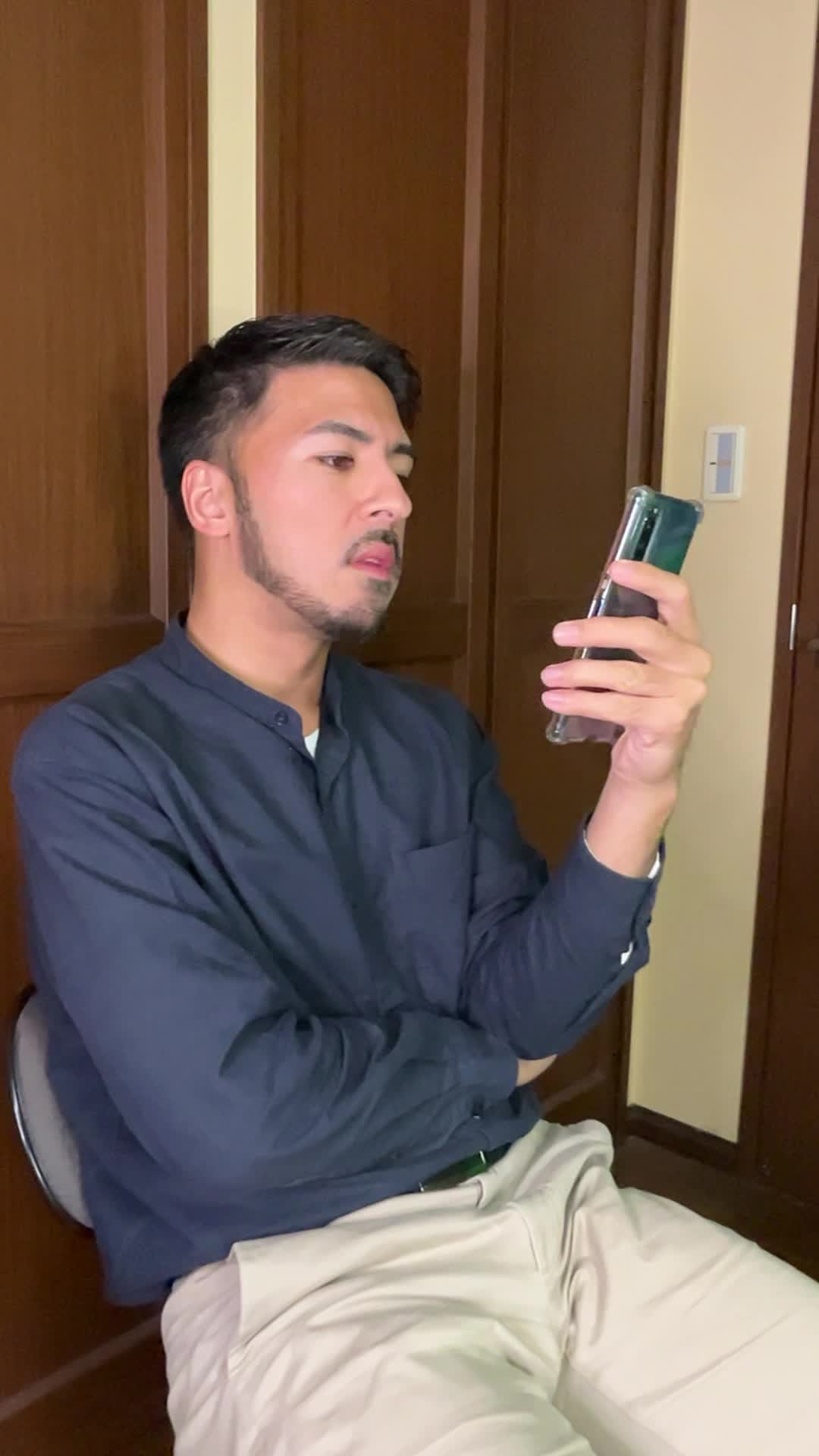 スマホで自撮りしながら、歯の色を確認して悩むような表情を浮かべる