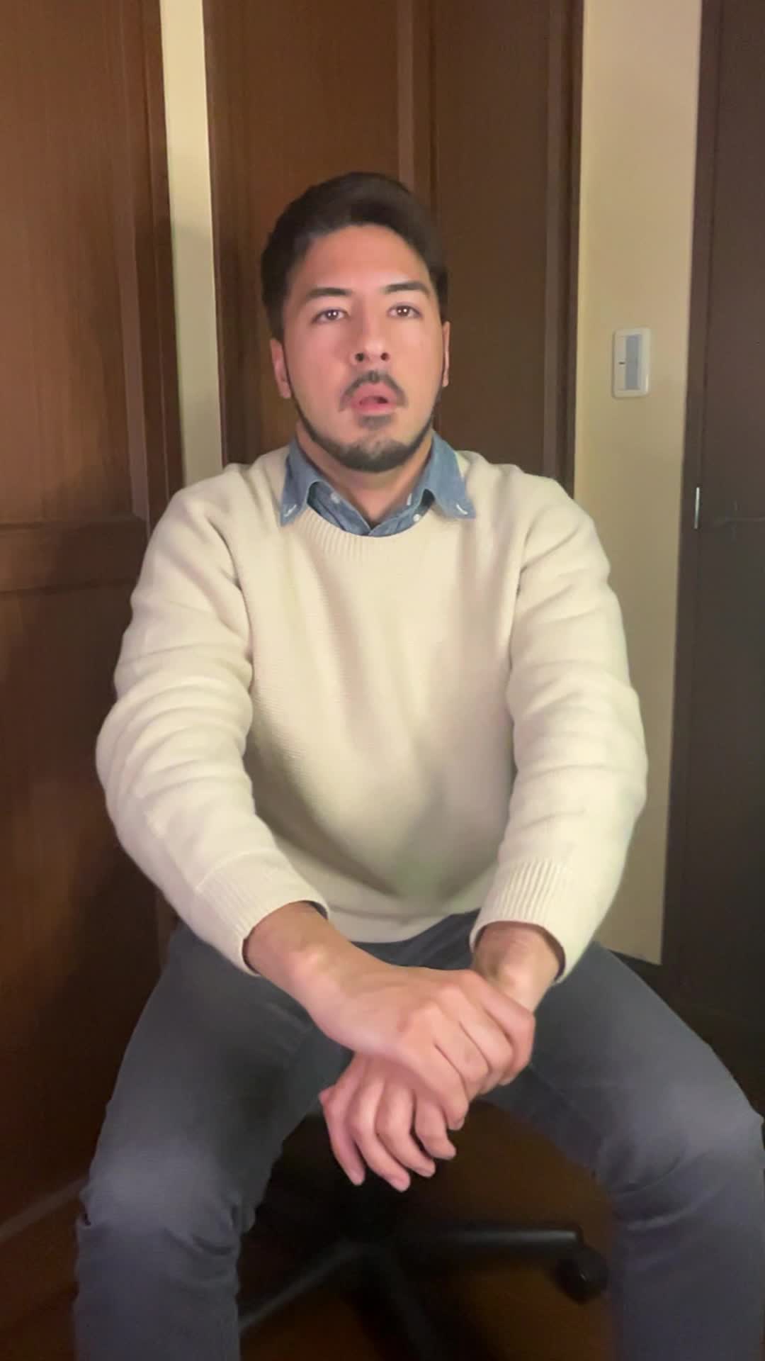椅子に座りながら体を前に倒し、背中を軽く伸ばしている