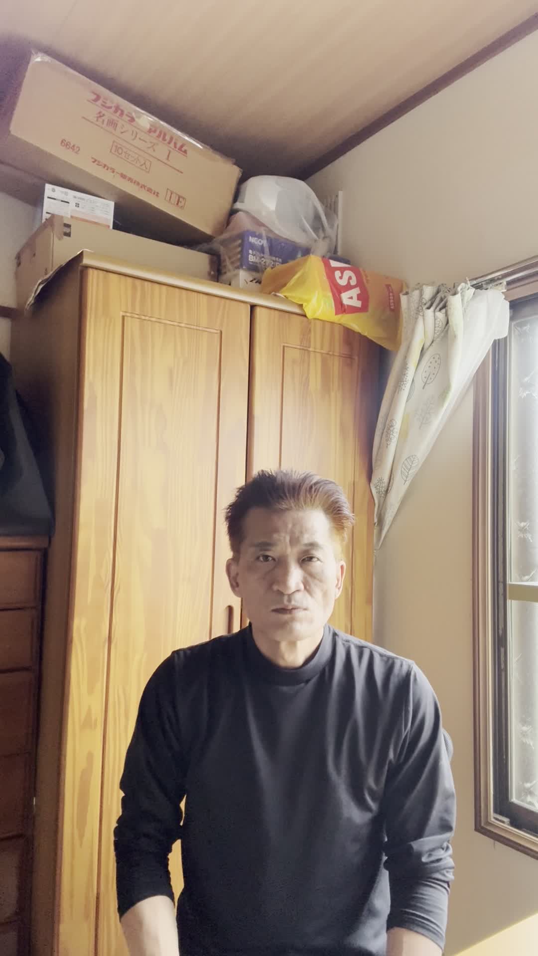 椅子から立ち上がり、「仕事中に疲れが出やすいのがつらい」と肩を回す動作