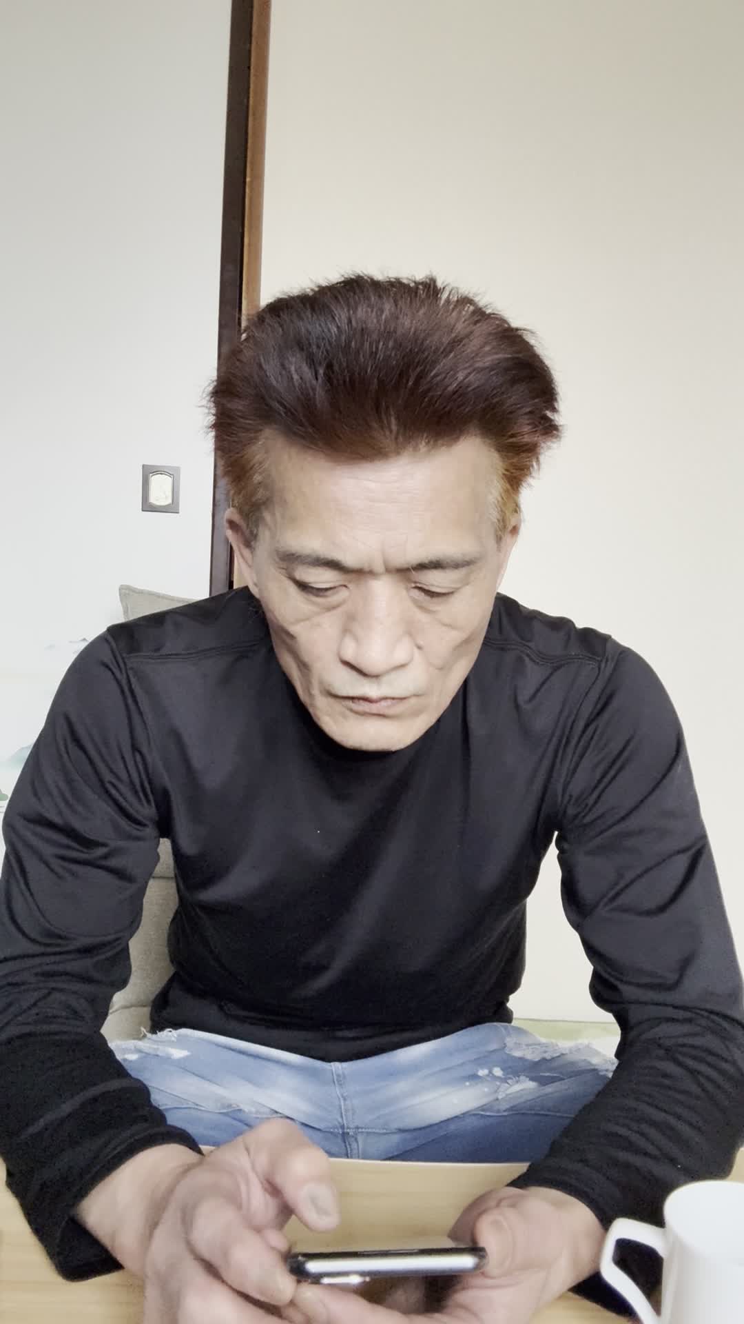 テーブルでスマホを見ながら、「体調を整える方法を必死に検索する」真剣な表情