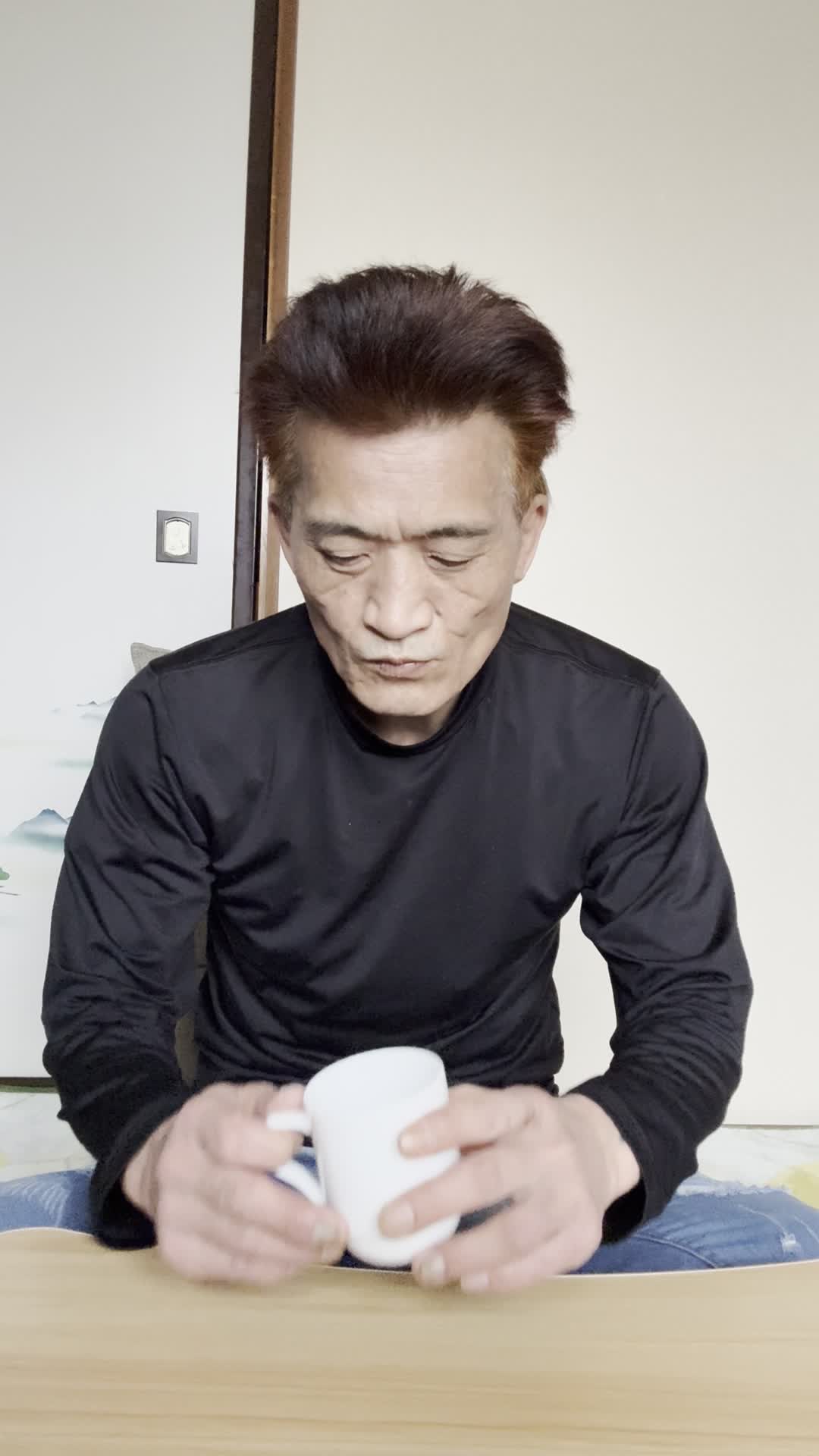 テーブルでカップを手に取り、「少しずつ体が良くなる期待を込めて飲み始める」微笑み